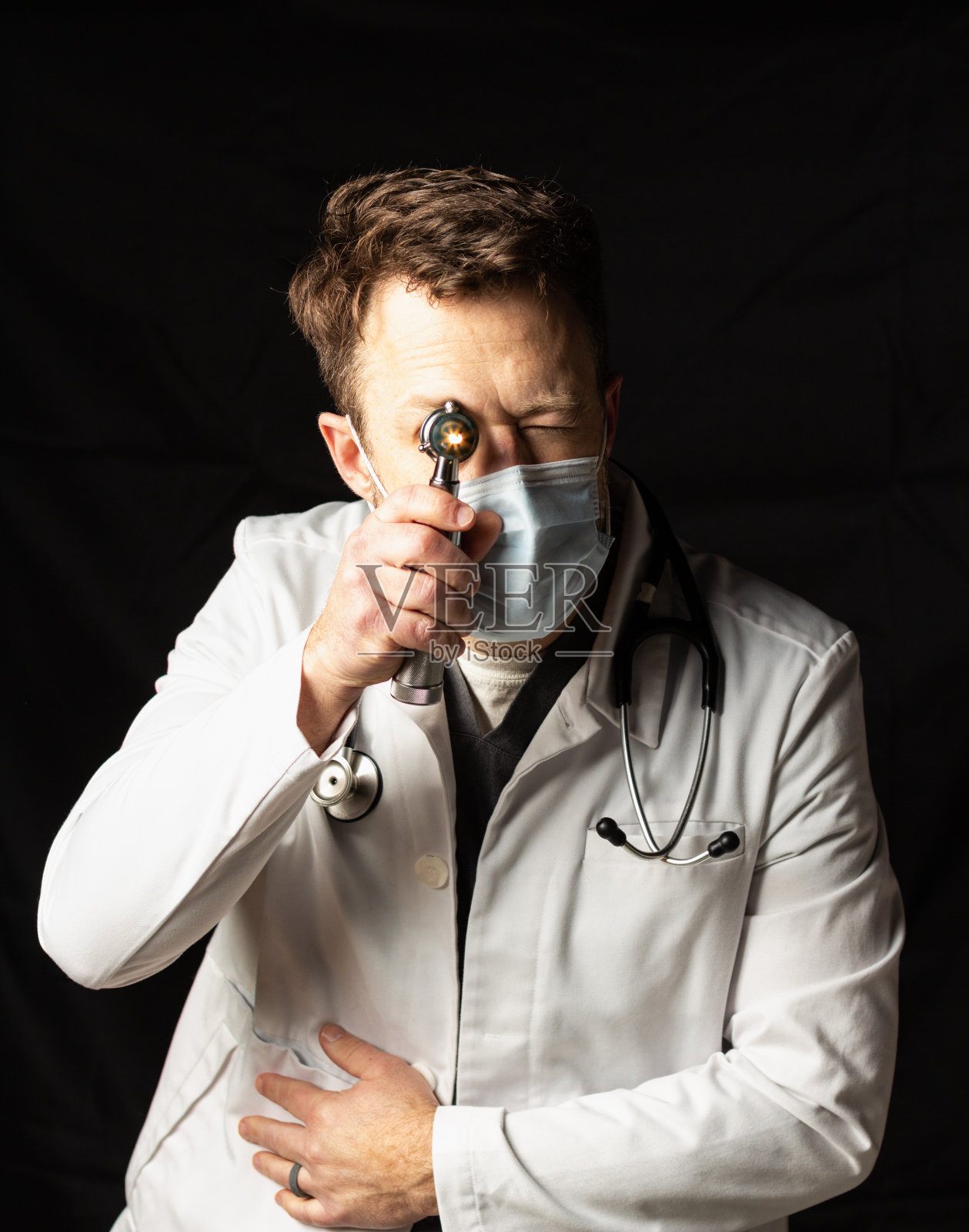 医生在黑暗的背景下用耳镜检查照片摄影图片