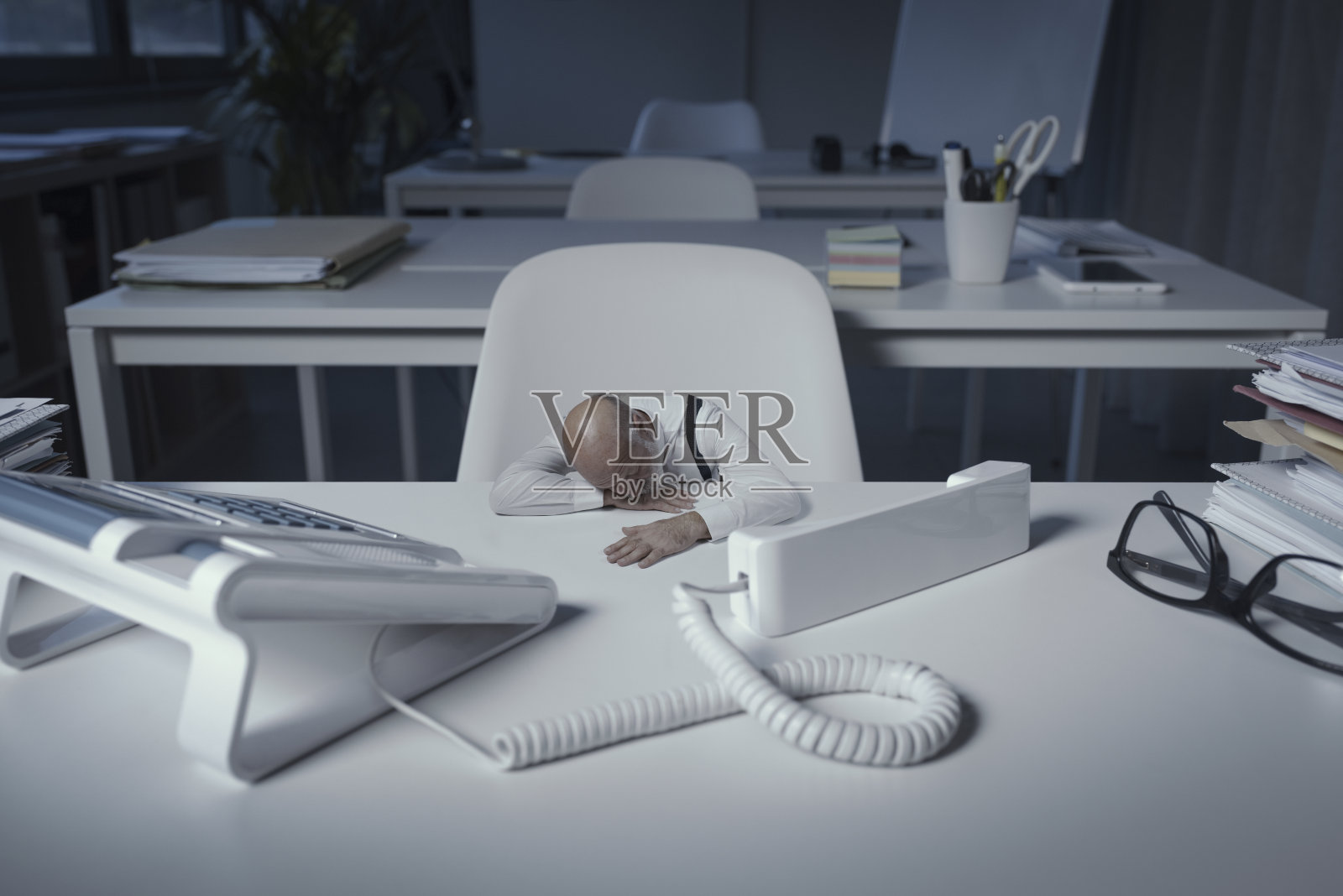 精疲力尽的小商人睡在办公桌前照片摄影图片