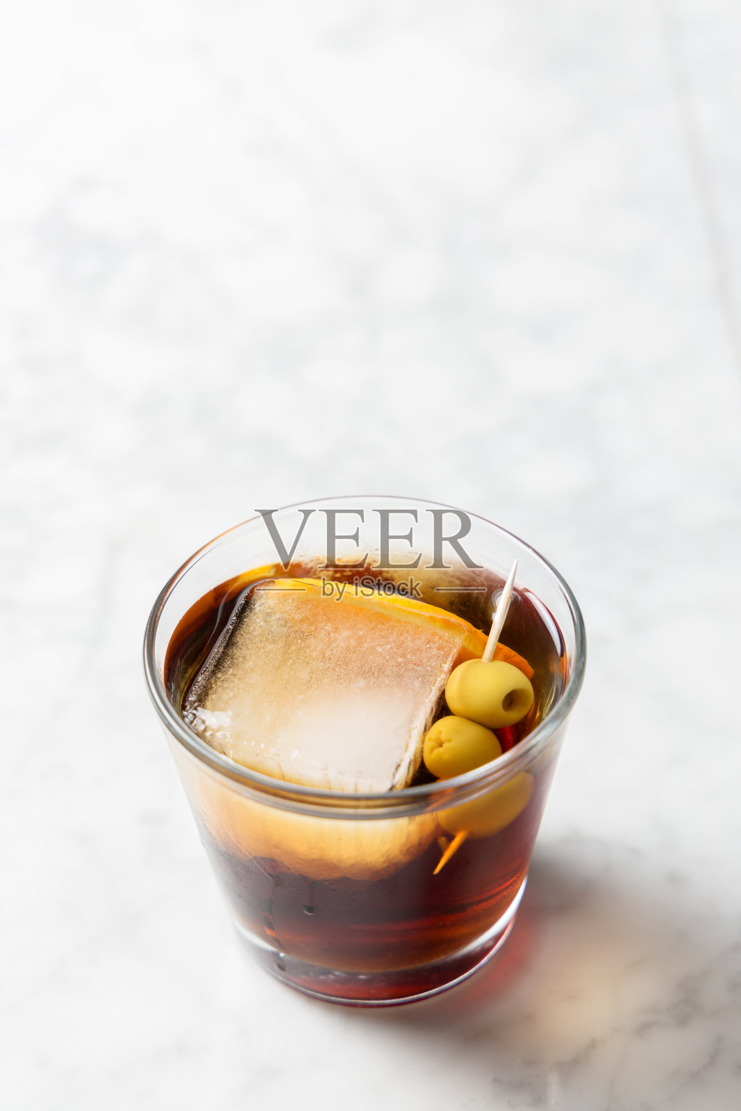 一杯加冰的苦艾酒，橙片和橄榄照片摄影图片