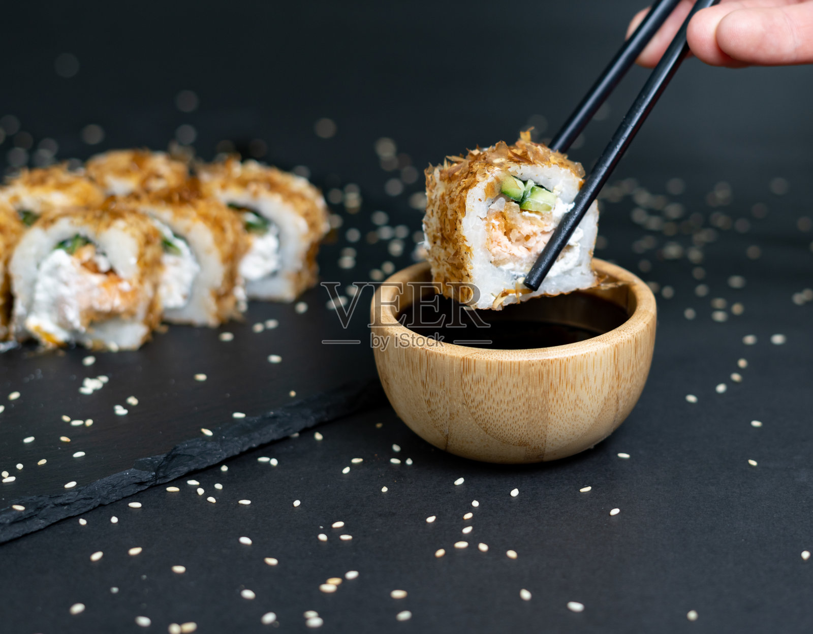 寿司卷配奶油芝士和鲣鱼干片。蘸酱卷在深色背景上照片摄影图片