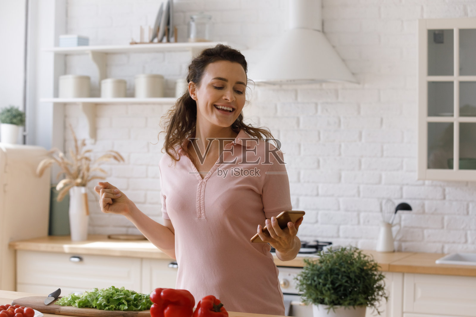 快乐的年轻女子听着音乐准备食物。照片摄影图片