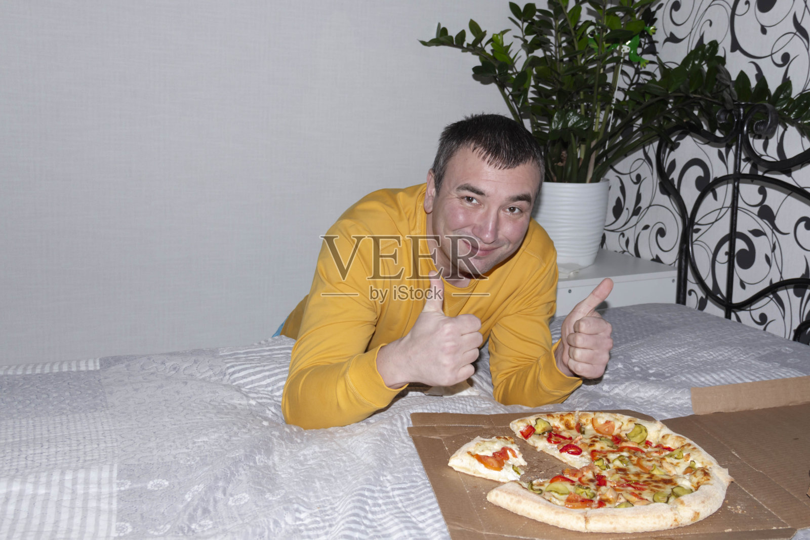 一个穿着黄色夹克的男人吃着美味而芬芳的披萨。照片摄影图片