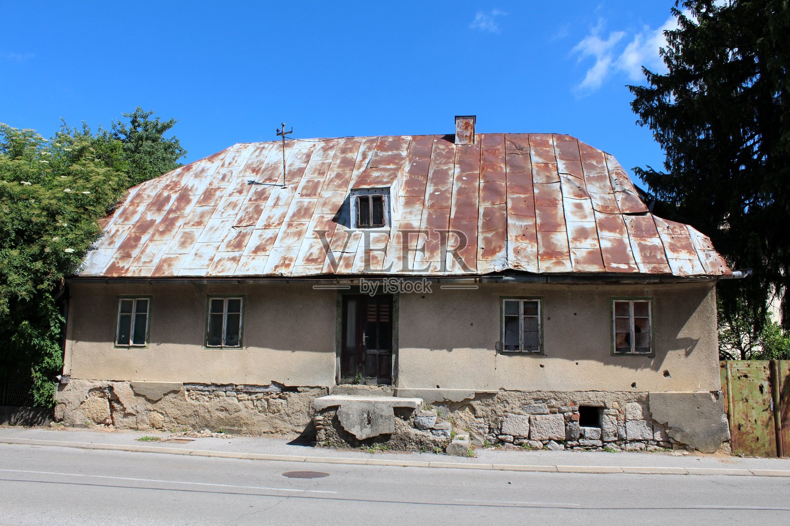 在破碎的石头和混凝土基础上的废弃家庭房屋的正面，受损的窗户周围的立面照片摄影图片