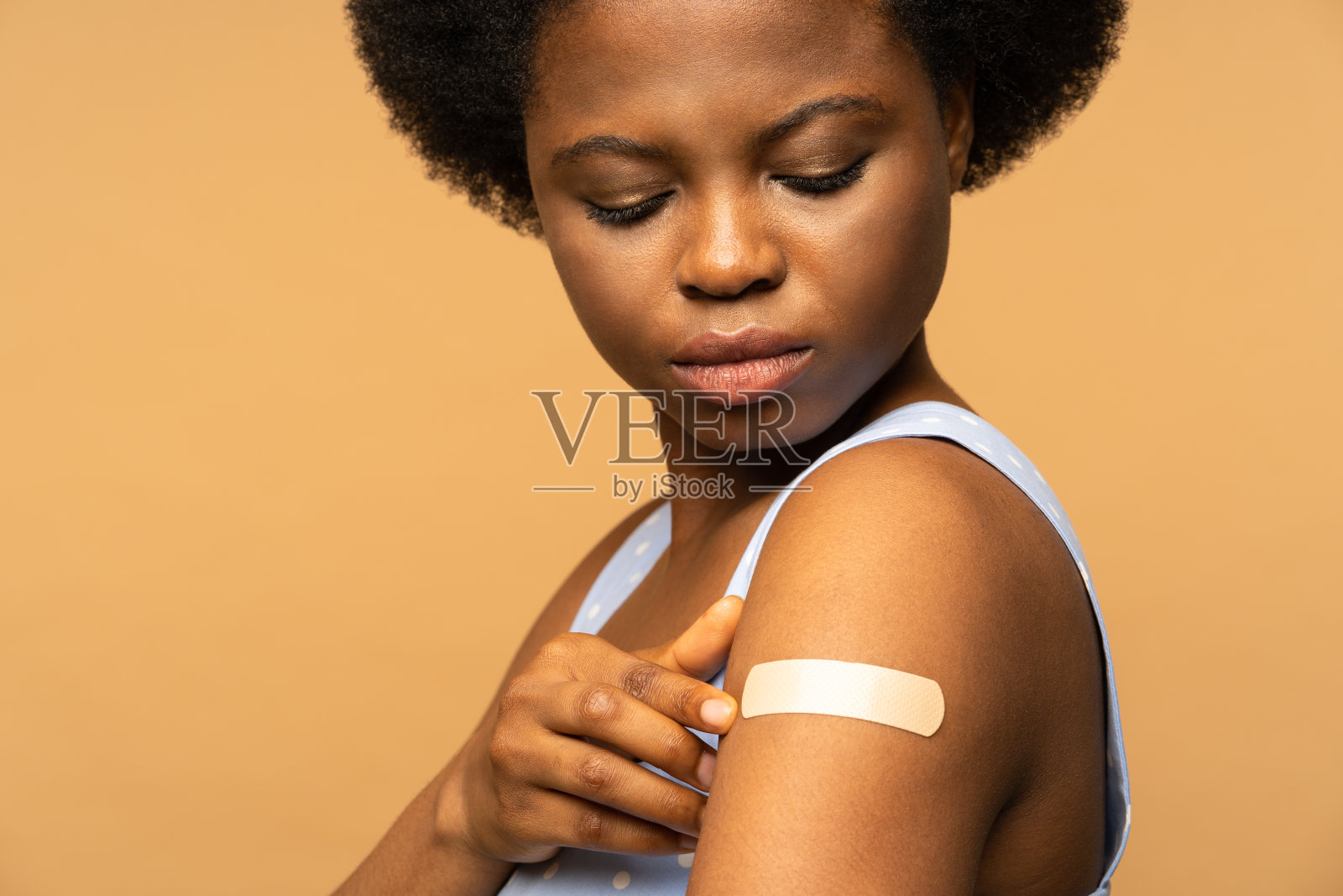 年轻女子看着肩膀上的膏药，正在接种冠状病毒疫苗。Covid-10疫苗注射照片摄影图片