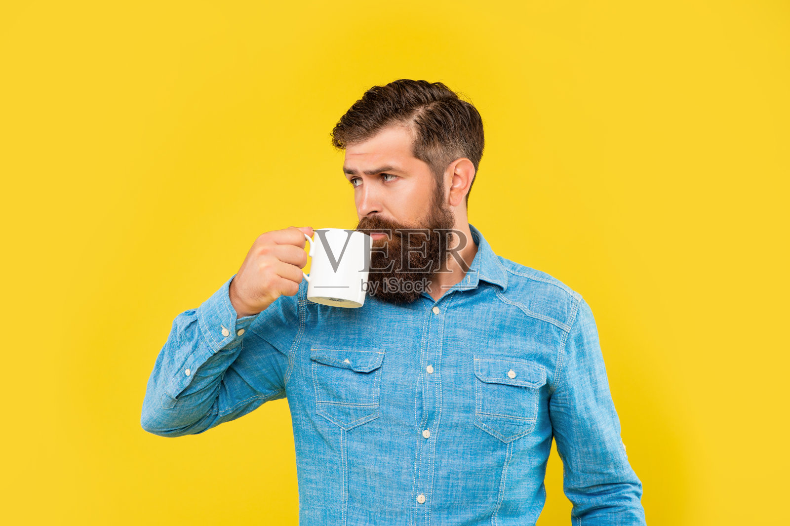 严肃的高加索人喝咖啡的杯子黄色背景照片摄影图片