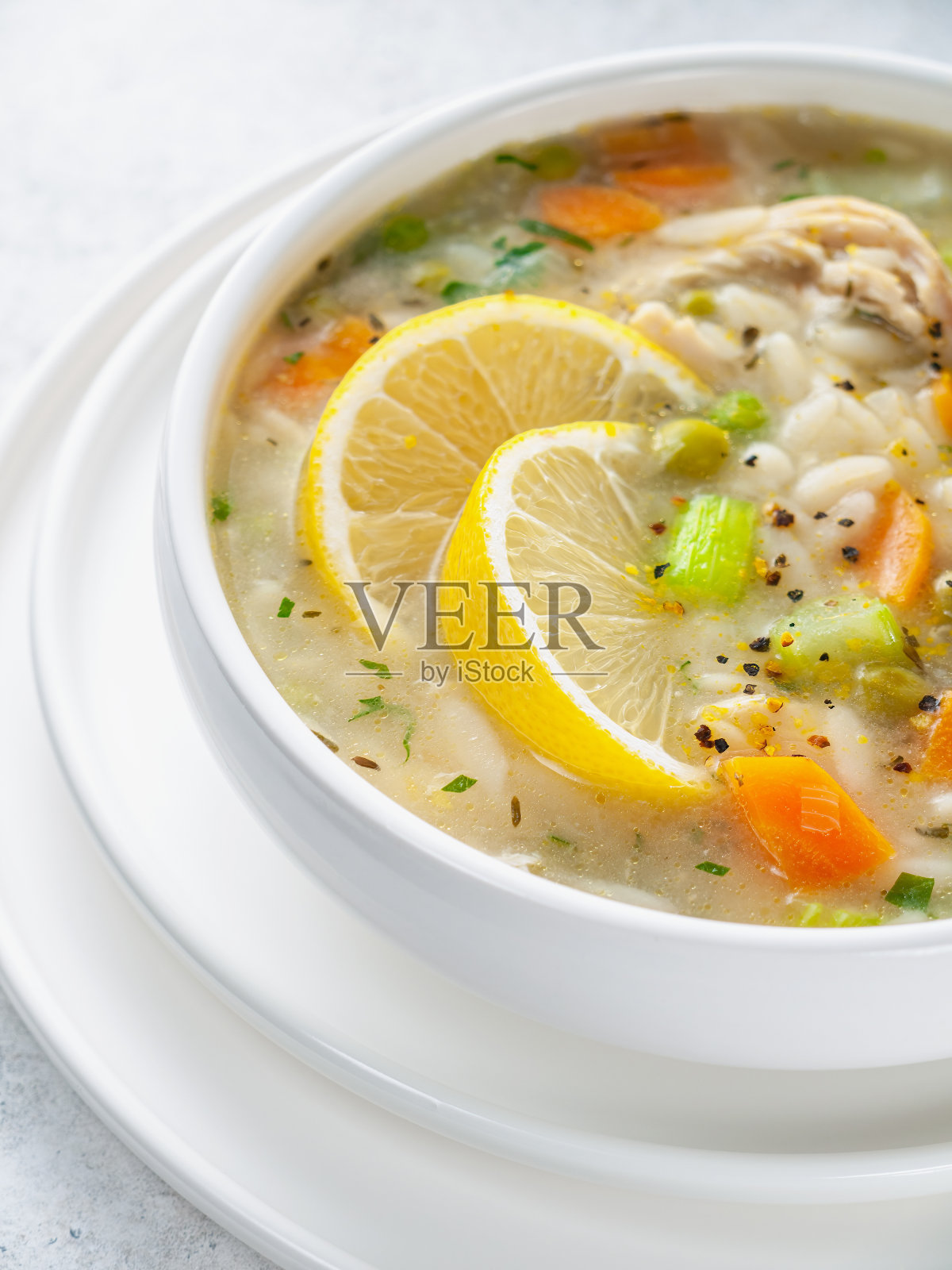 柠檬鸡汤的特写镜头。意大利菜。白色的碗。光背景。照片摄影图片