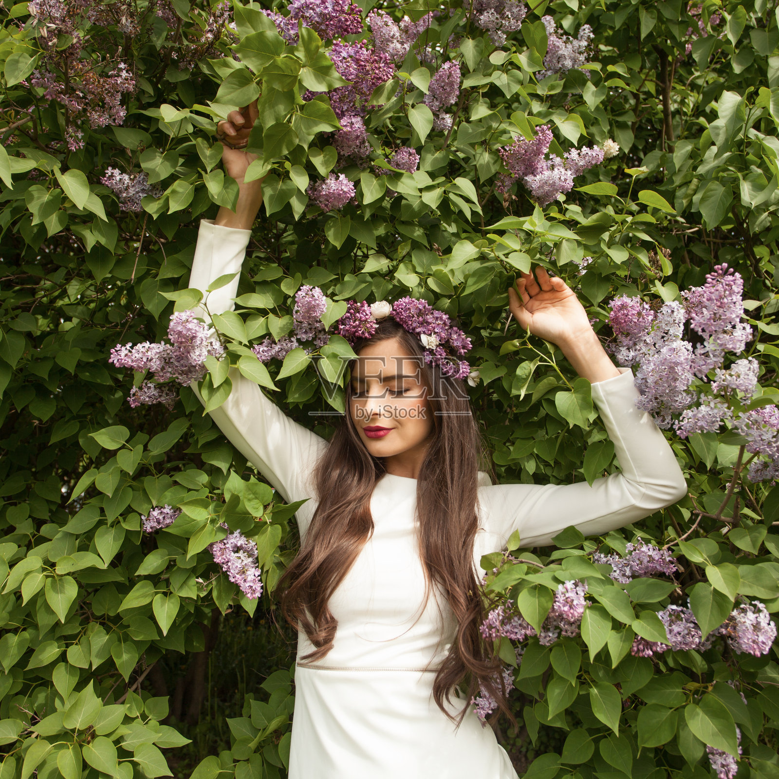 迷人的年轻女子在白色的连衣裙摆姿势在花园与开花的树木照片摄影图片