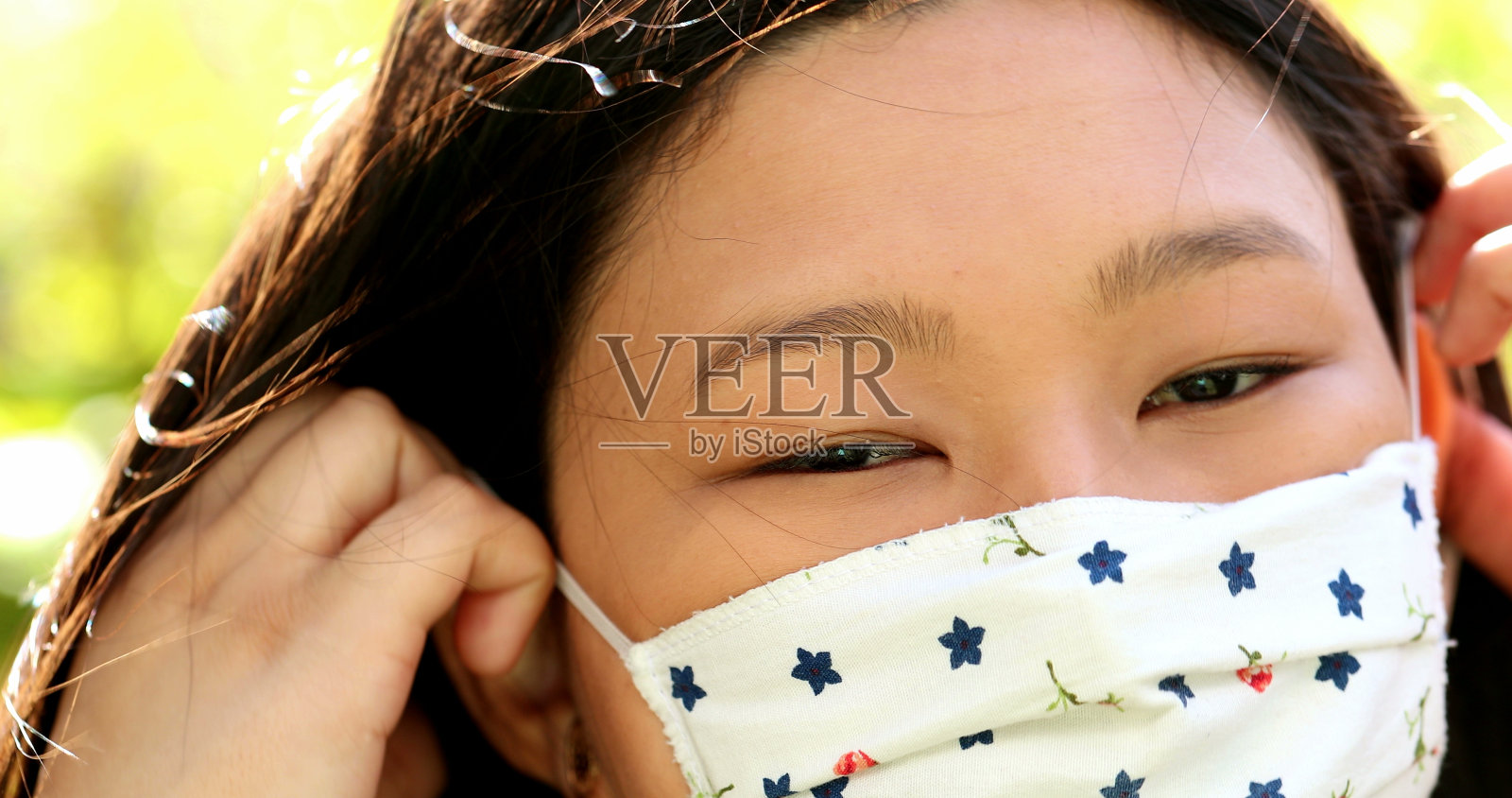 一名亚洲年轻女子把新冠肺炎口罩放在外面，看着镜头照片摄影图片