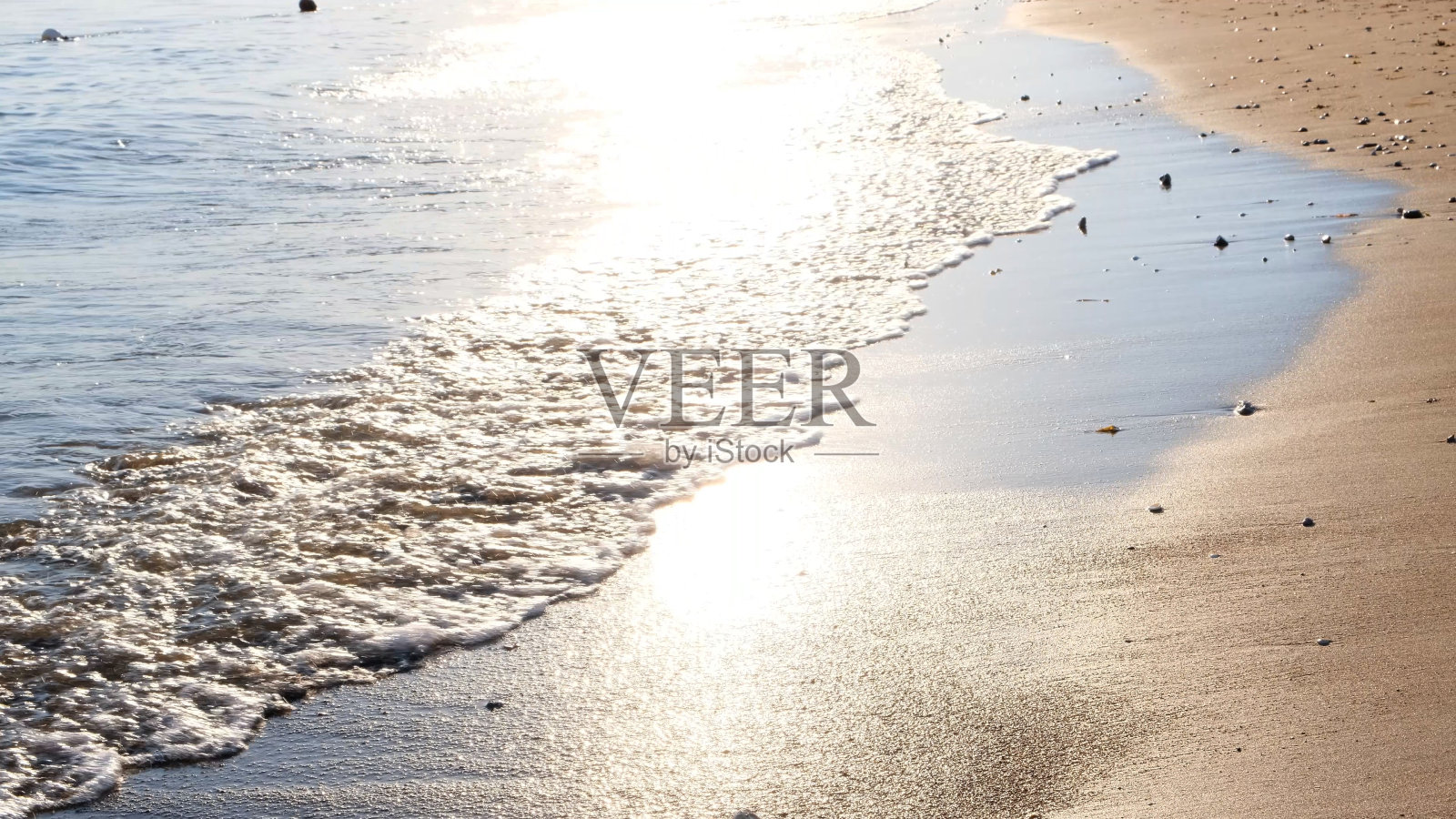 柔和的波浪，蓝色的大海在沙滩上与太阳在日落照片摄影图片