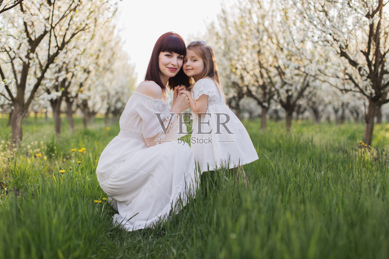 母亲和女儿在春天的花园面对面摆姿势照片摄影图片