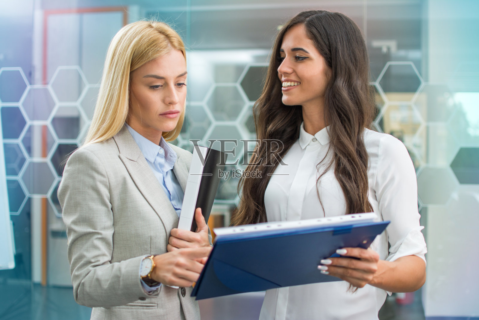 两个女业务同事在办公室审阅文件。照片摄影图片