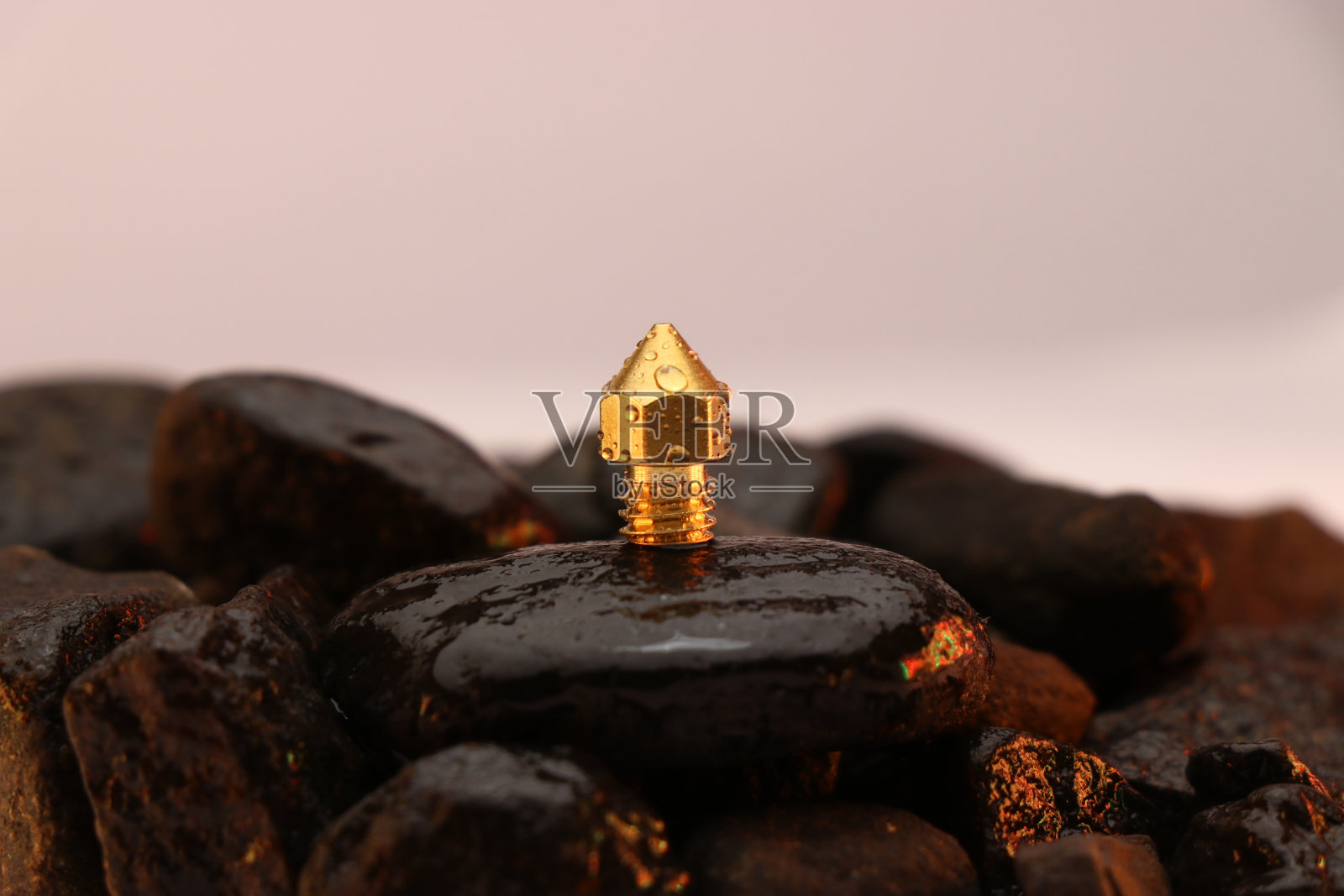 3D打印机的黄铜喷嘴在潮湿的石头上，3D打印机的备件照片摄影图片