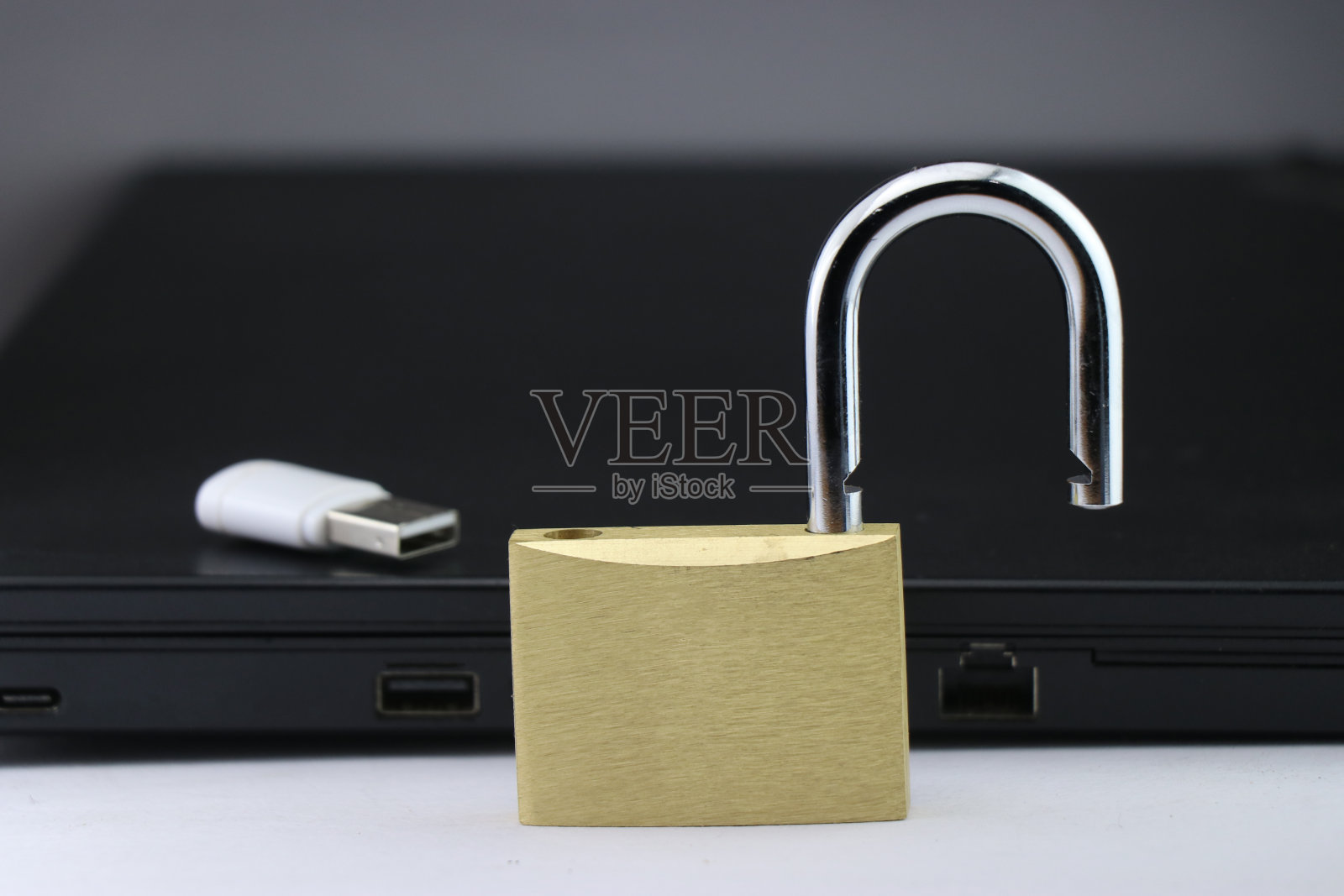网络安全或数据安全概念，使用带有数据存储设备和后台笔记本电脑的金属锁照片摄影图片