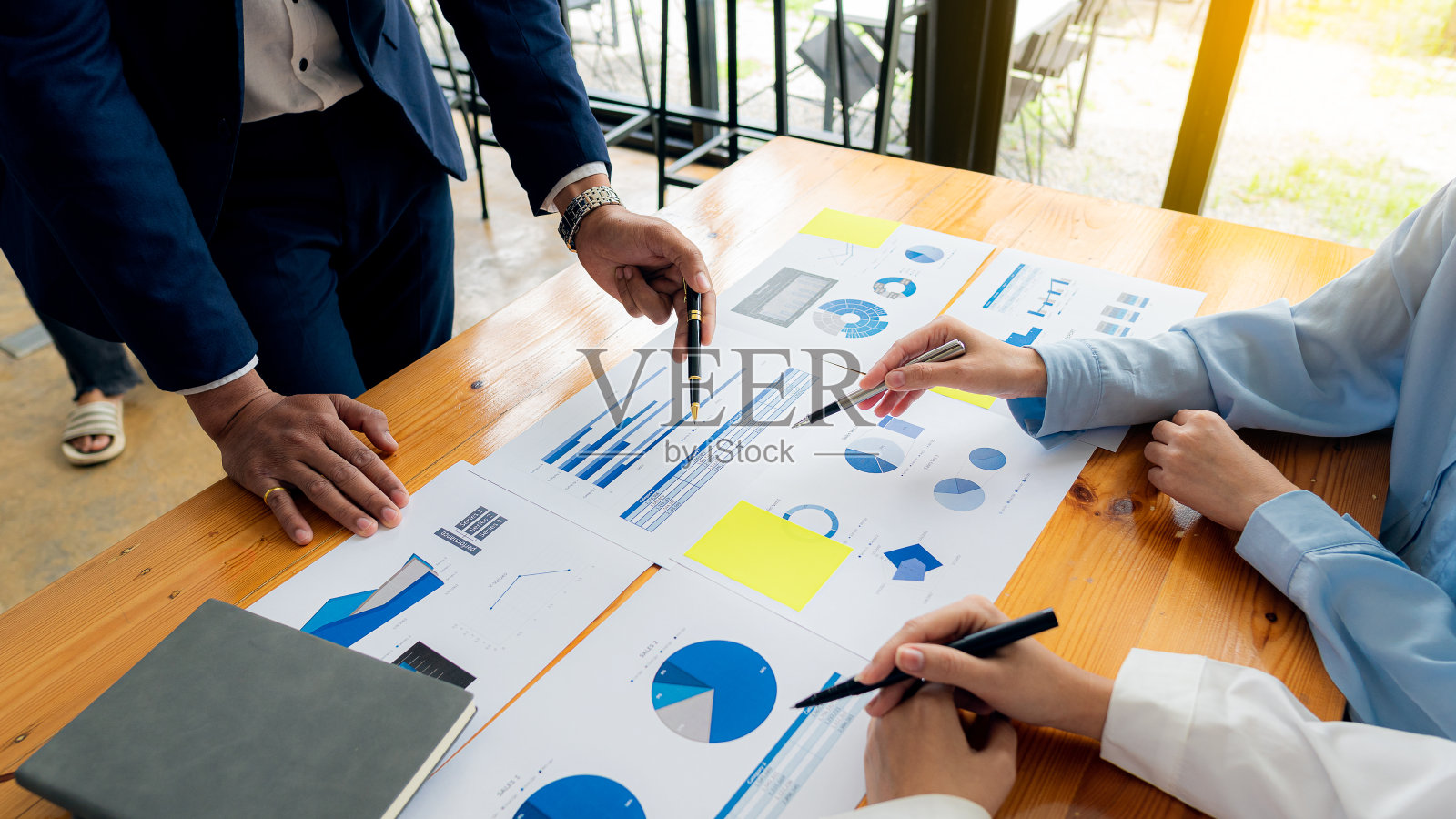 一群商人开会分析财务图表数据，为商业会计计划出谋划策。在办公室的桌子上放一个笔记本电脑和一个计算器。照片摄影图片