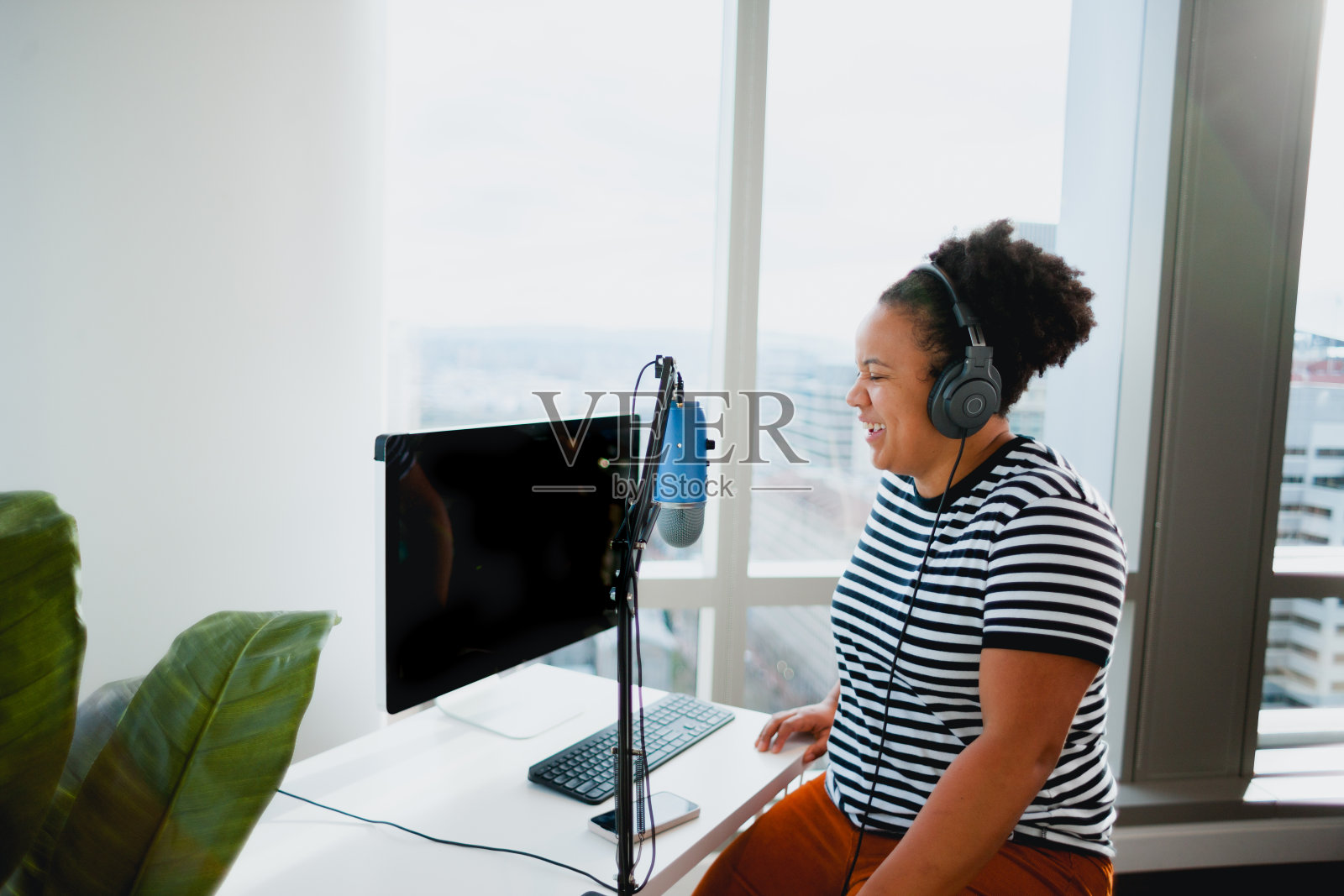 快乐的黑人妇女在她市中心的办公室做播客照片摄影图片