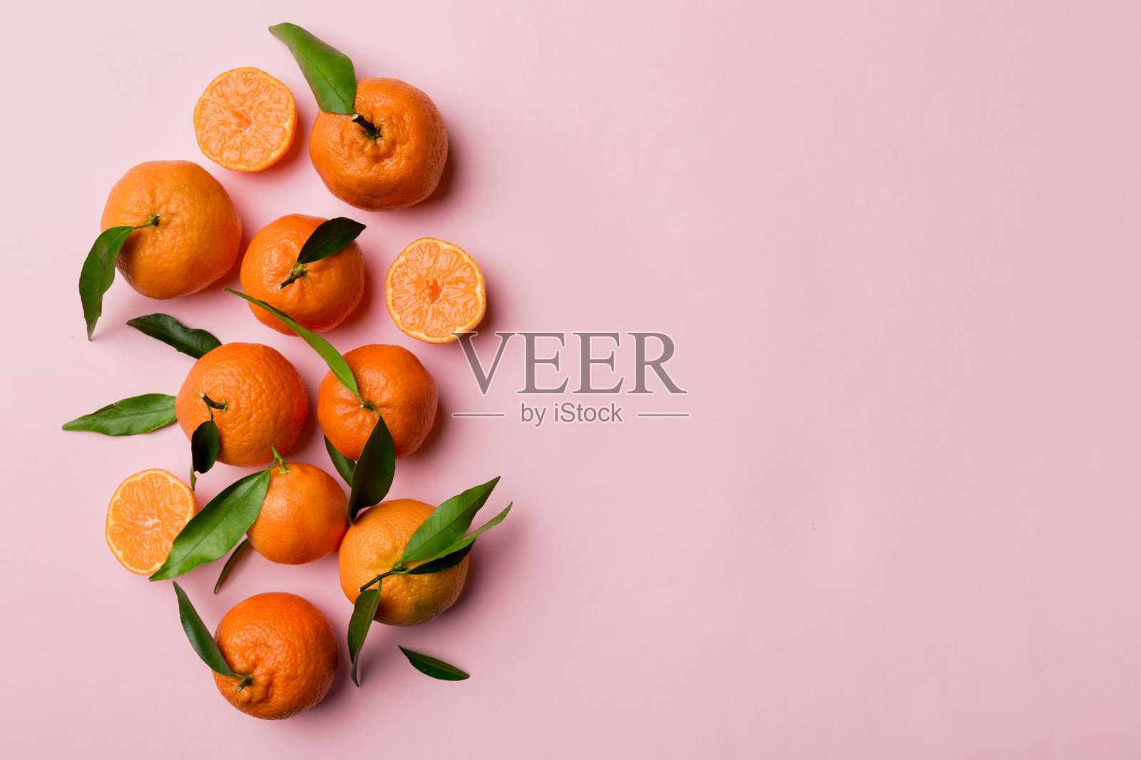 许多新鲜成熟的柑橘与绿色叶子彩色背景，俯视图，文本空间照片摄影图片