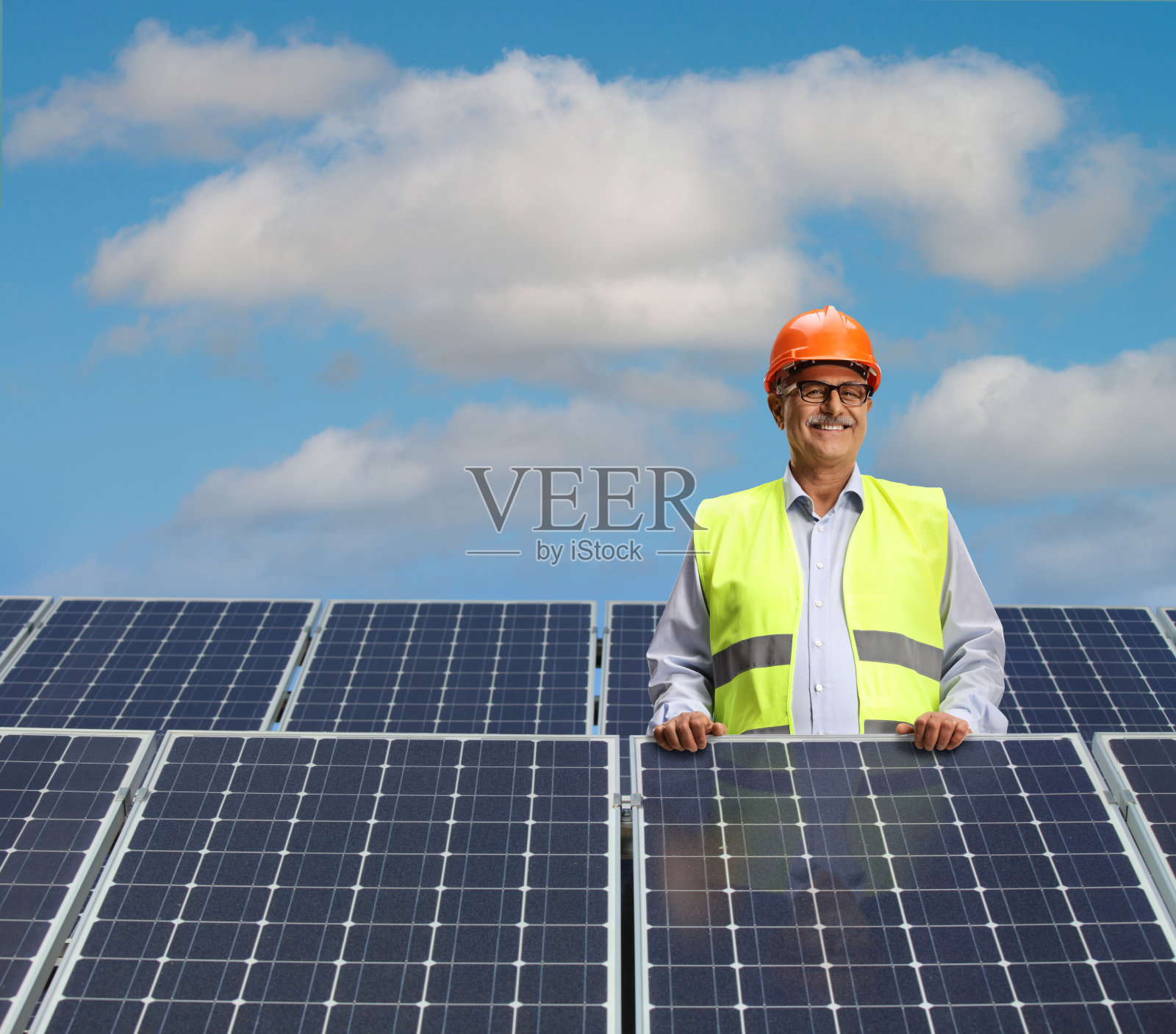 中年男工程师在太阳能电池板之间摆姿势照片摄影图片