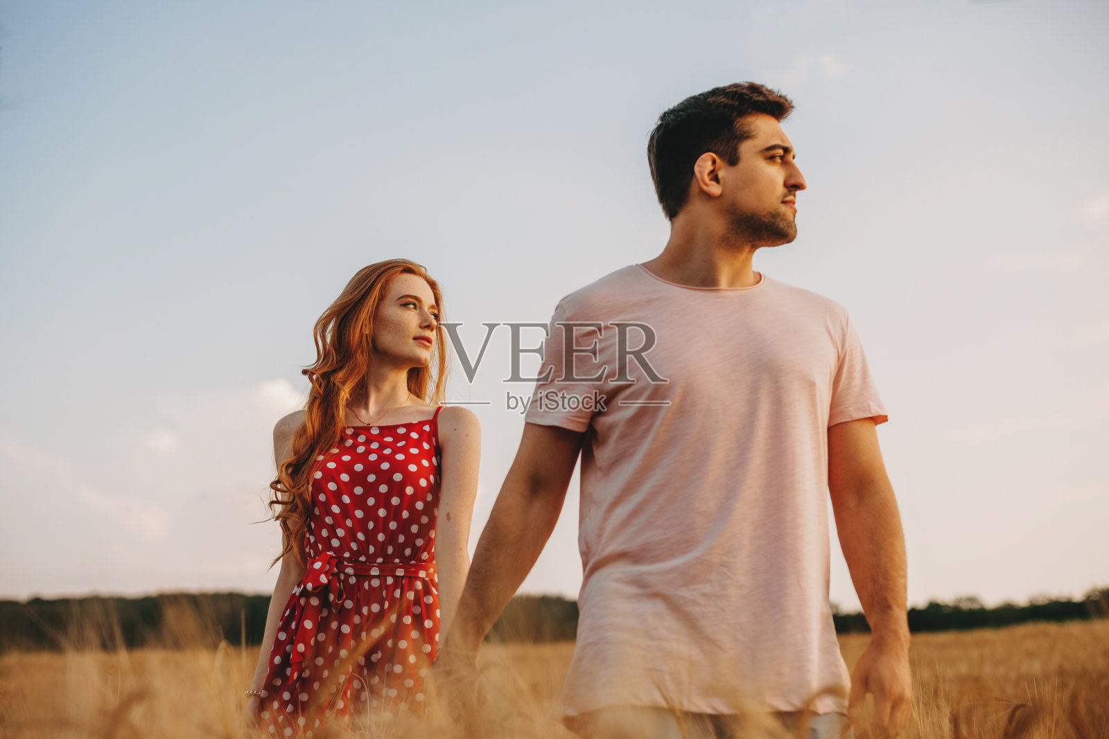 夕阳西下，情侣们手牵着手在田野里散步，发现新的风景如画的地方。暑假。家庭的周末。照片摄影图片