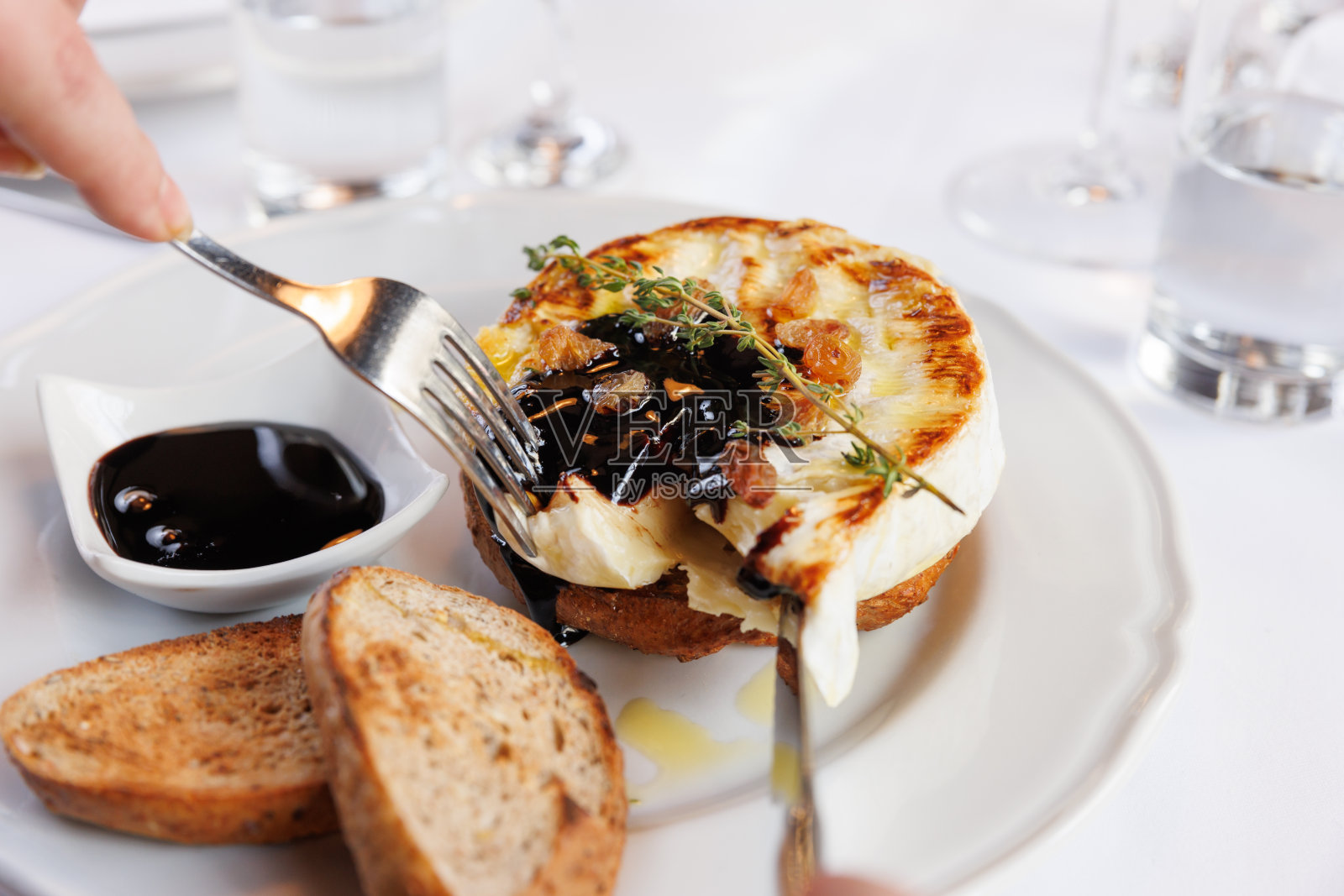 拿着叉子在用香醋调味的manouri奶酪上，与面包片一起食用照片摄影图片