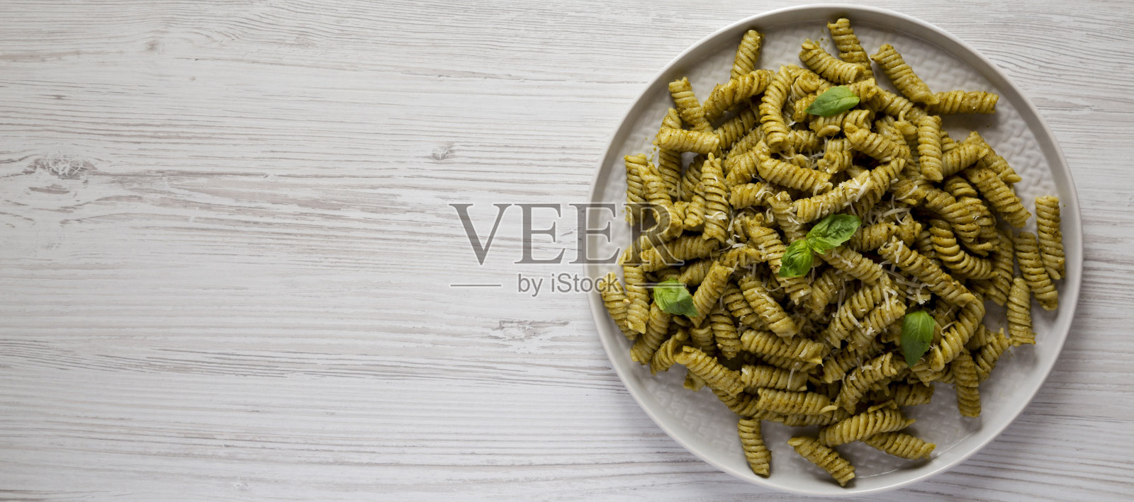 自制香蒜沙司扭面在一个白色的木制表面的盘子上，俯视图。俯视图，从上面，平躺。副本的空间。照片摄影图片