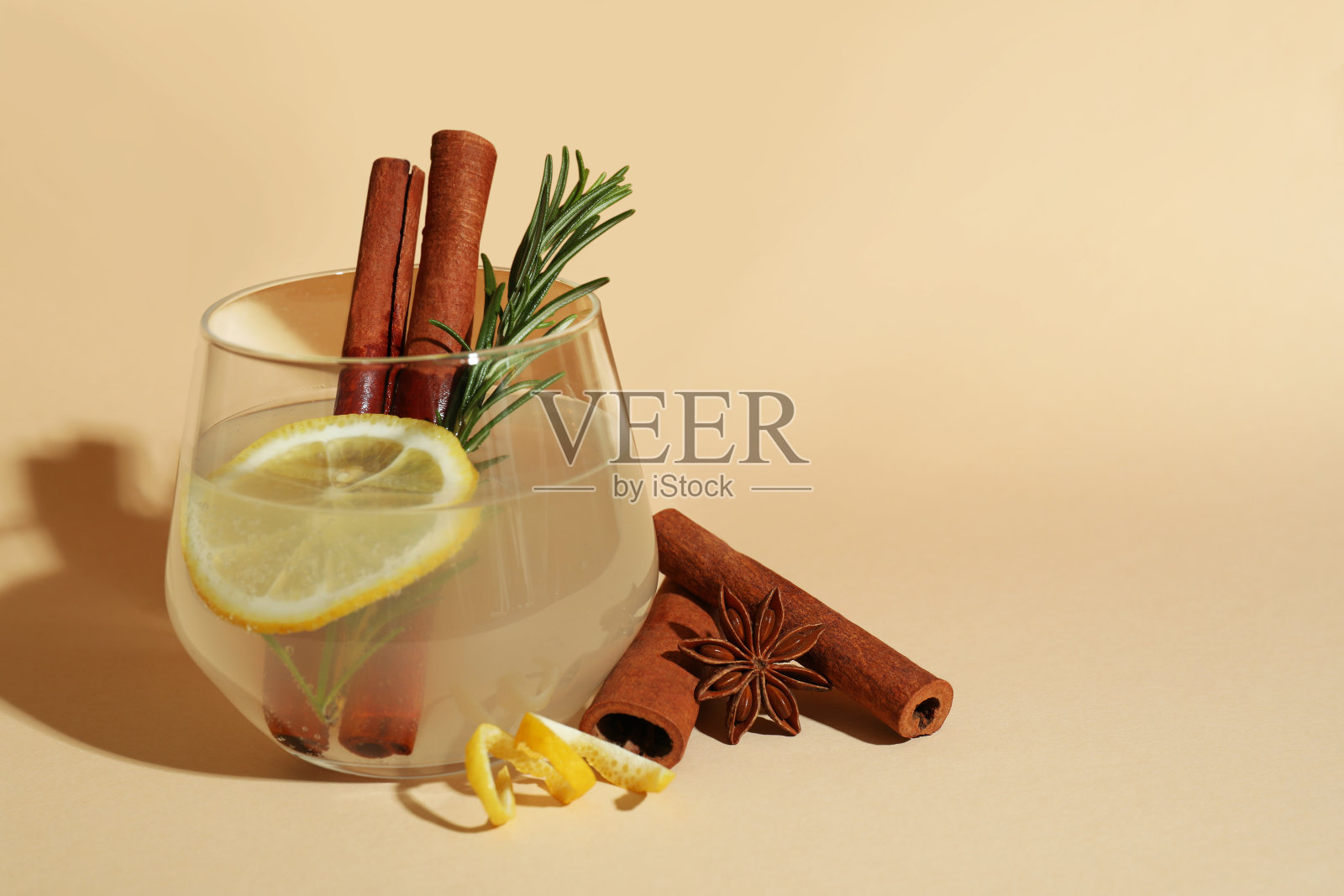 一杯柠檬水，米色背景，肉桂和迷迭香照片摄影图片