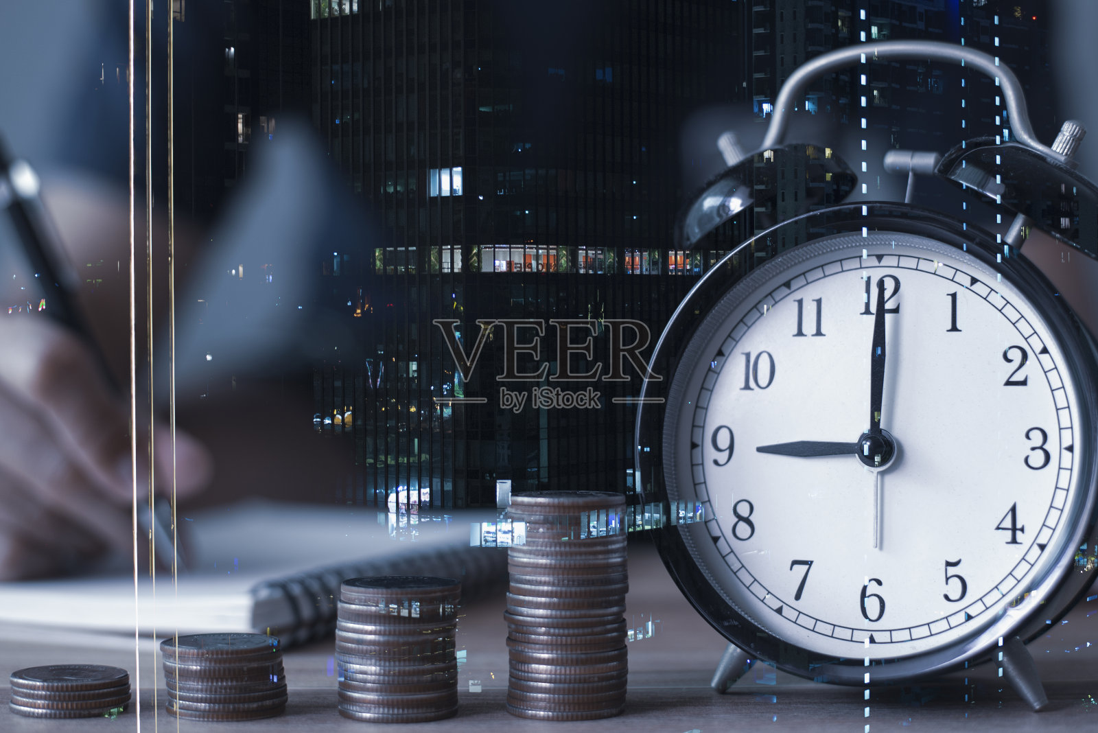 年轻的商人在纳税和城市风景上做笔记的双重曝光，桌子上摆放着一排排的硬币和钟表，显示每年的纳税期限。照片摄影图片