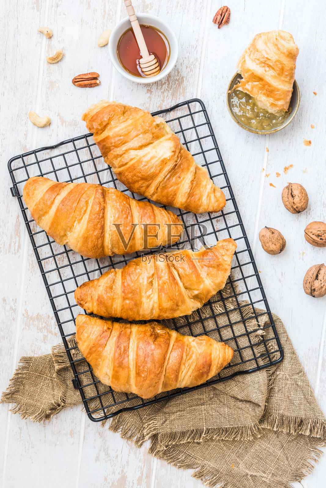 早餐场景与牛角面包，蜂蜜，坚果和咖啡在白色木质背景，俯视图照片摄影图片