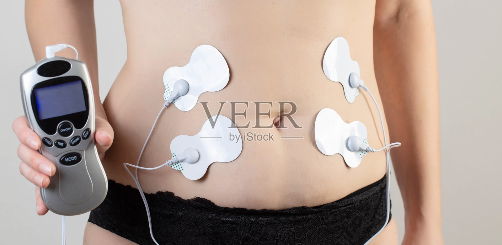 现代电子针灸，燃烧腹部脂肪和加强肌肉在女孩的身体，特写照片摄影图片