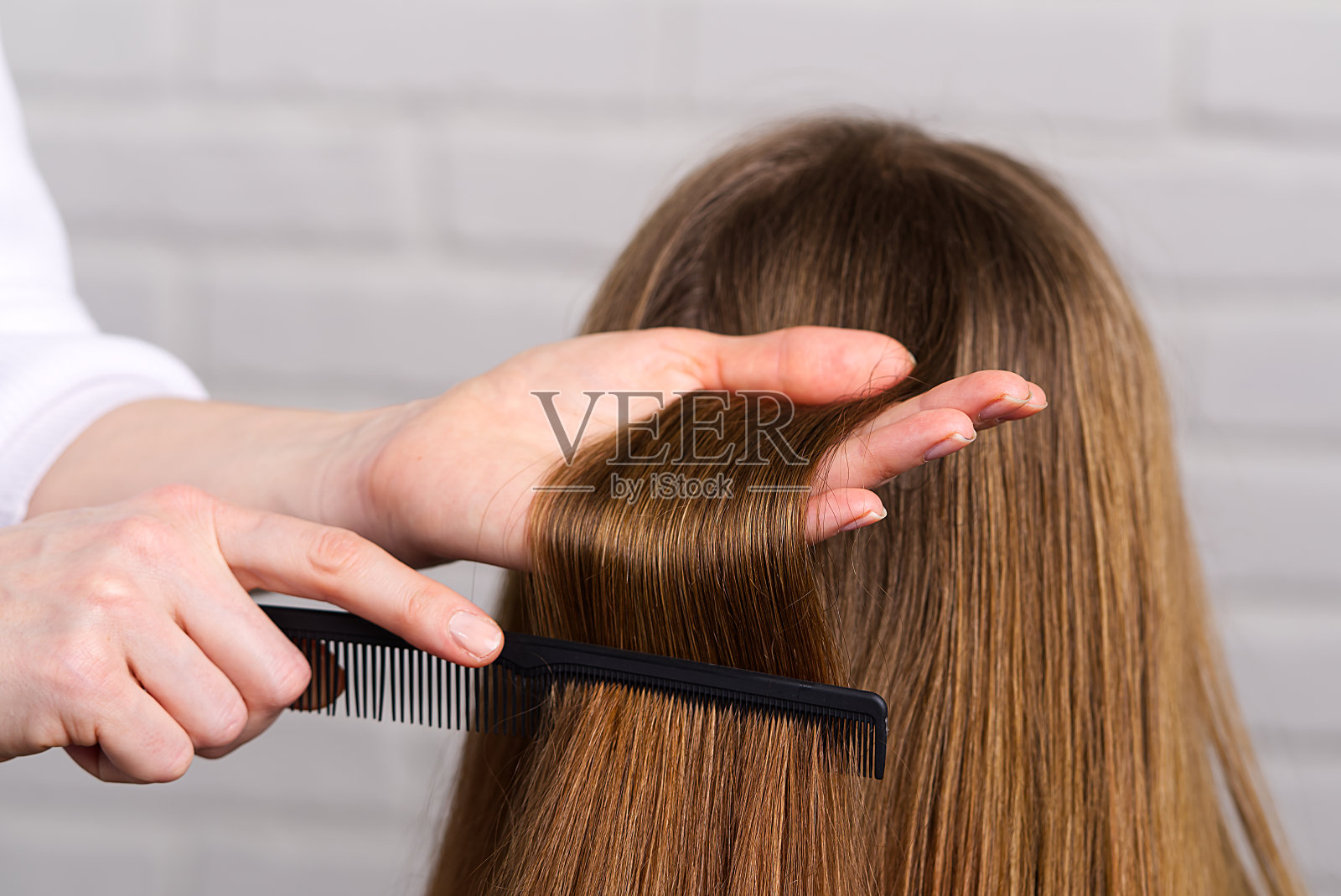 女人头发护理。美发师在美容院为年轻女孩做发型。照片摄影图片