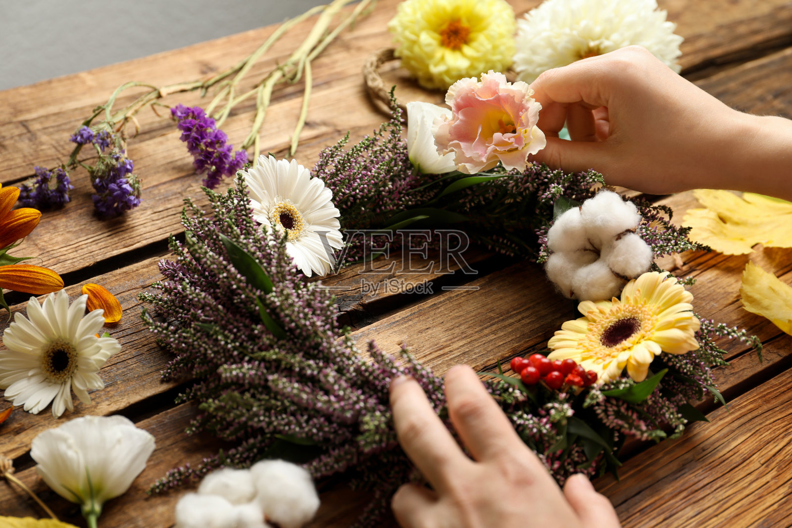 花商在木桌上制作美丽的秋季石南花花环，特写照片摄影图片