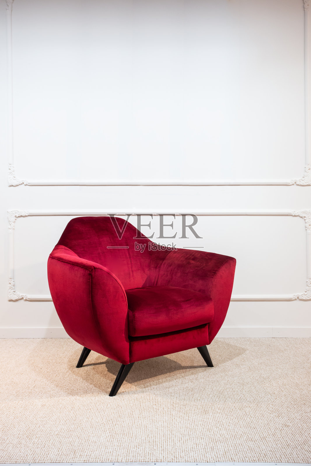 一张天鹅绒的猩红色扶手椅站在白色墙壁的空房间里:用选择性聚焦的特写照片照片摄影图片