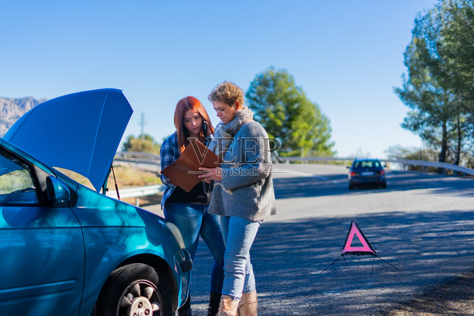 两个女人开着坏了的车打电话来照片摄影图片