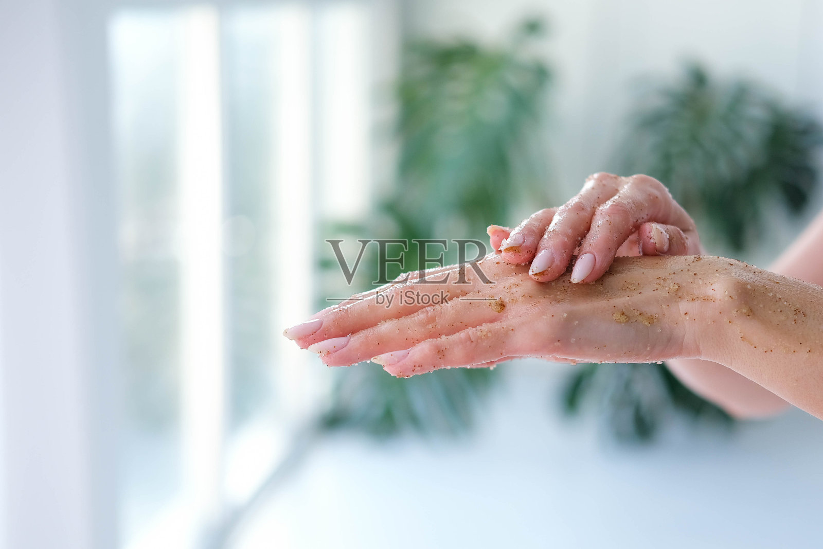 特写的女人是手与咖啡按摩磨砂在怪物模糊的背景。美容、手部护理、spa化妆品、美容理念。照片摄影图片