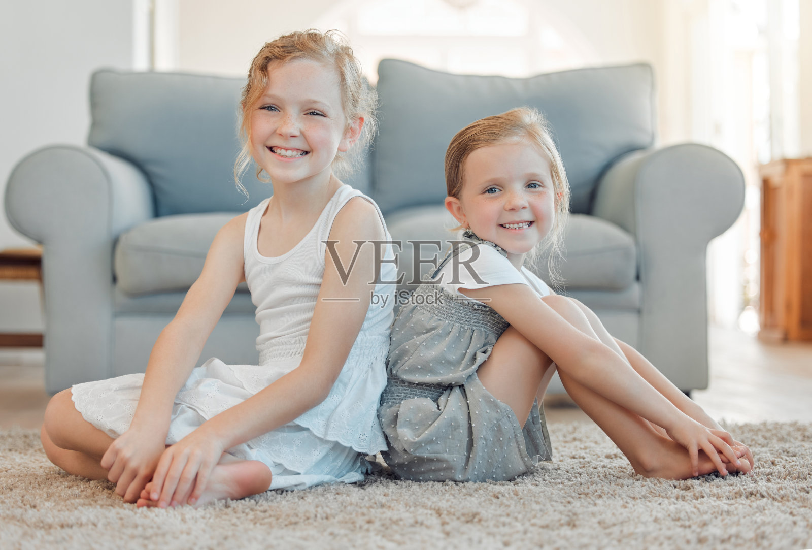 两个小女孩坐在家里的地板上亲密无间的照片照片摄影图片
