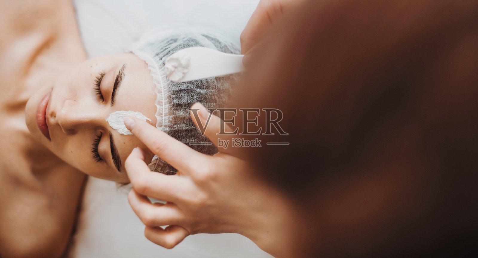 美容面膜在美容院女性面部的应用。面部护理。美容护肤。照片摄影图片