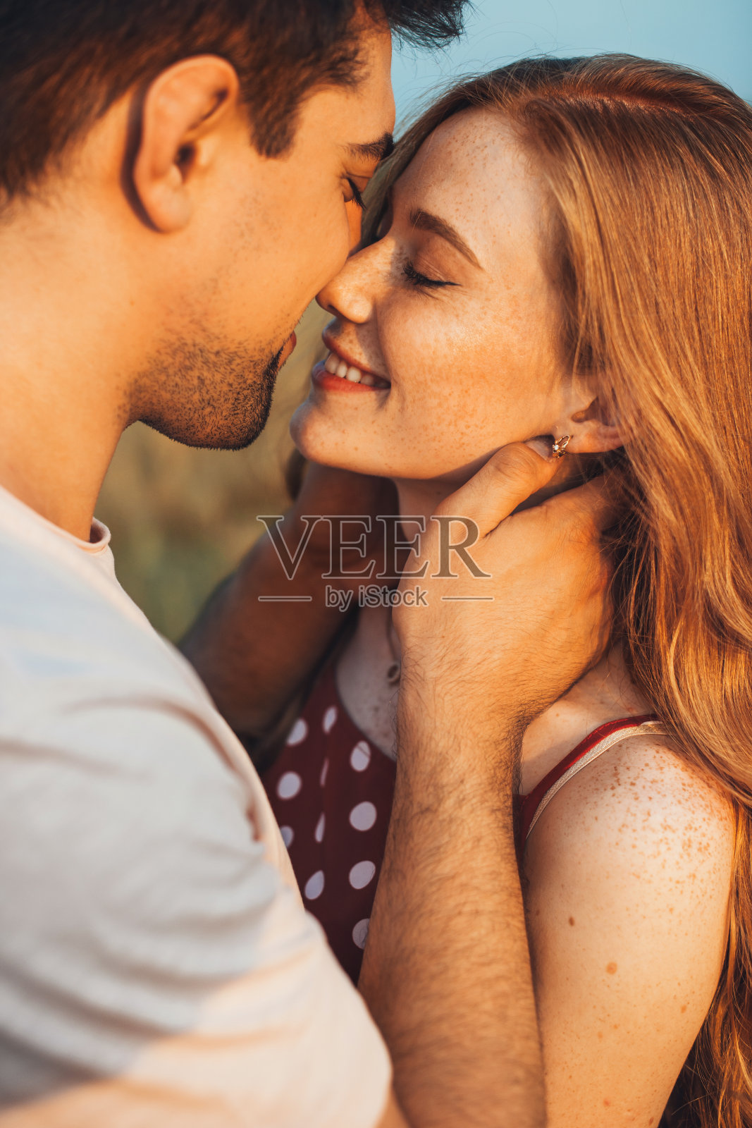 户外肖像的白种人夫妇摆姿势亲吻在麦田。年轻漂亮的女孩。特写肖像。照片摄影图片