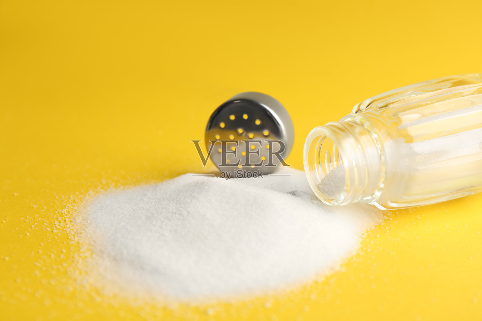 黄色背景上撒盐和摇瓶，特写镜头照片摄影图片