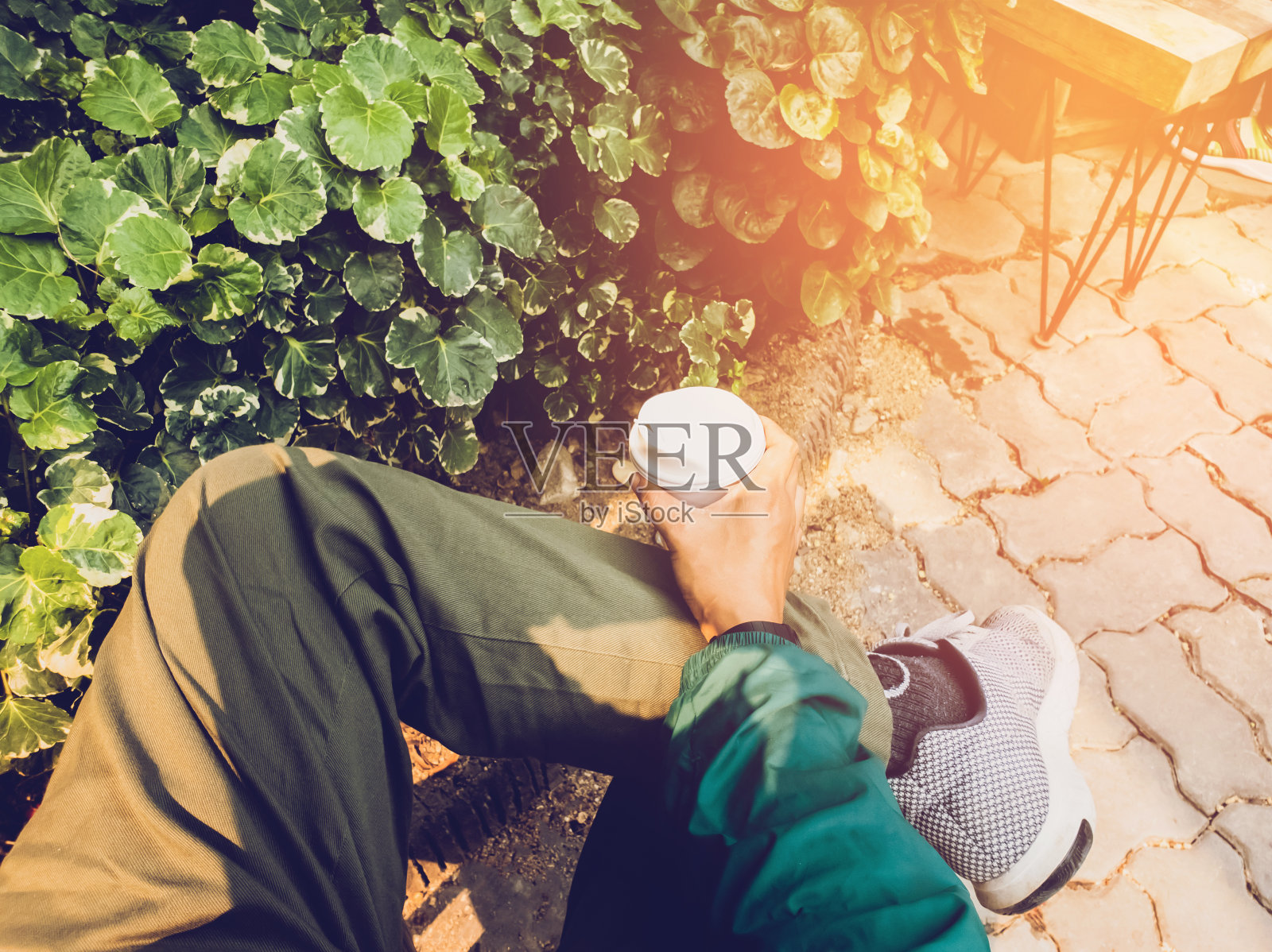 近距离的人们坐在椅子上，手握热咖啡杯，在大自然的背景和阳光下，在户外吃和喝咖啡的生活方式照片摄影图片