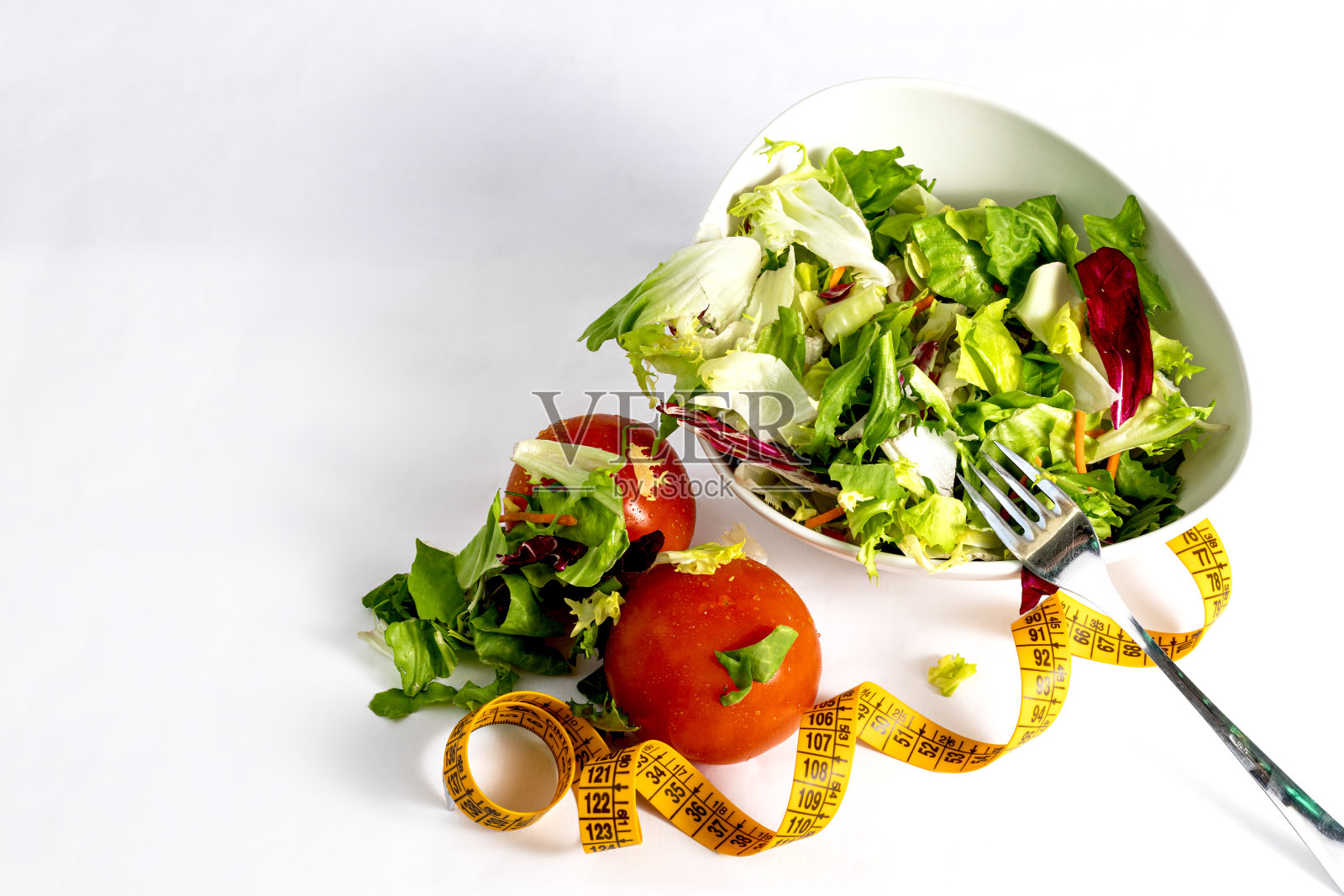 生菜和西红柿沙拉碗和卷尺在白色背景上照片摄影图片