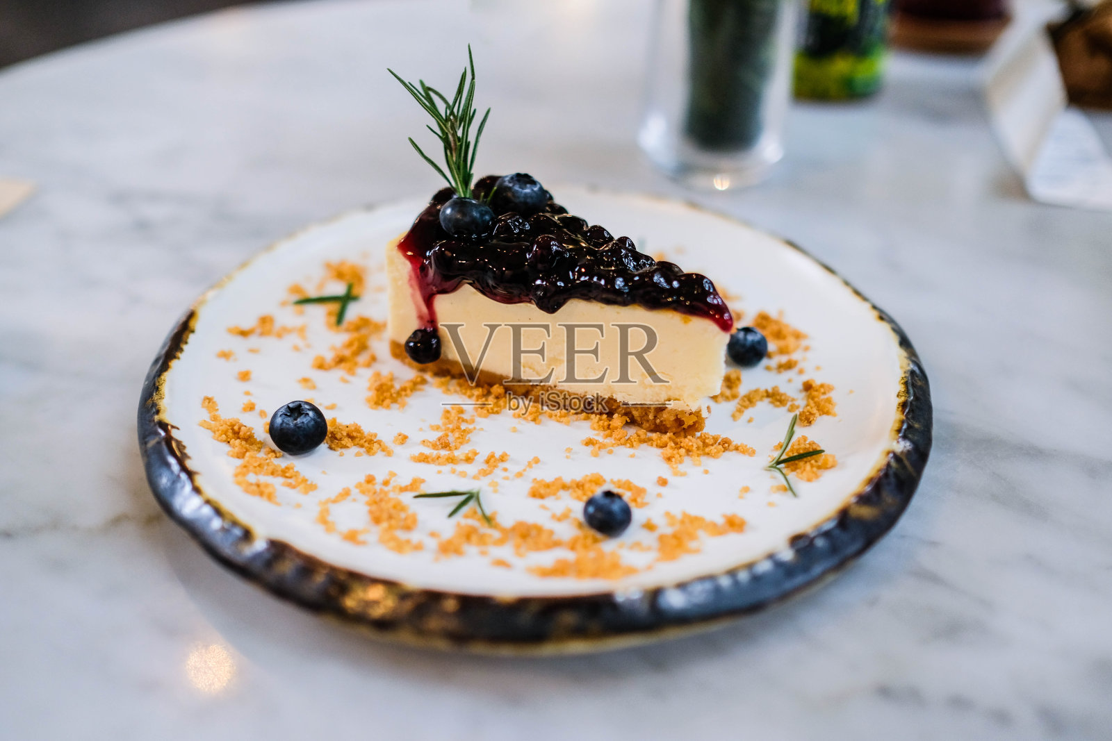 桌上有一块蓝莓芝士蛋糕。照片摄影图片