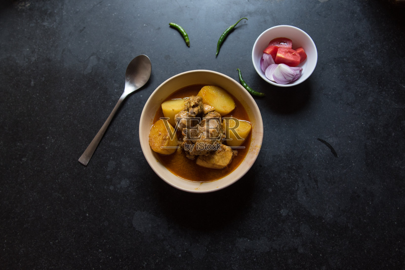 印度风格的咖喱鸡被盛在一个深色背景的碗里。照片摄影图片