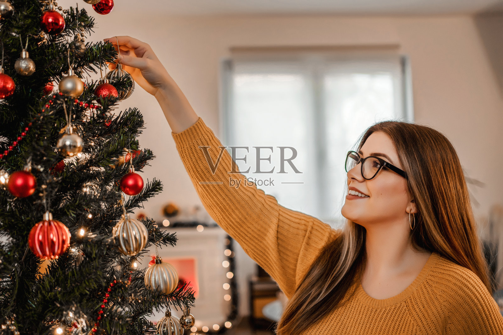 漂亮的年轻女人在客厅装饰圣诞树照片摄影图片