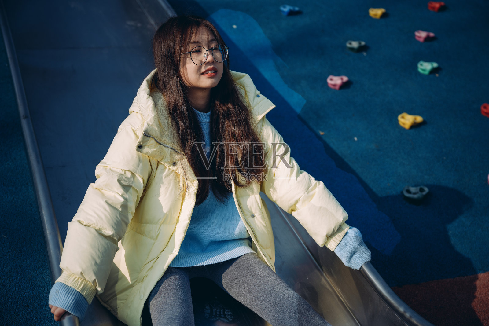 亚洲女孩在阳光明媚的日子里玩滑梯照片摄影图片