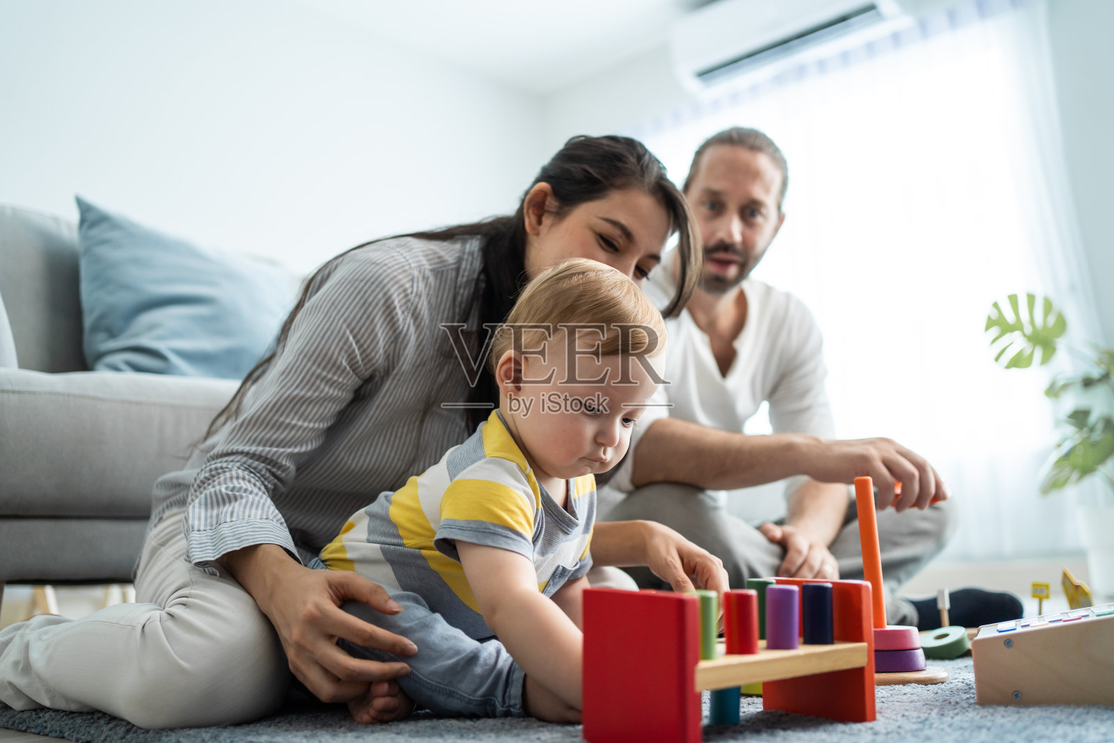 白种人快乐的爱的父母与幼儿在客厅玩。有吸引力的夫妇，父母花时间与年幼的婴儿儿子在房子里。家庭活动关系概念。照片摄影图片