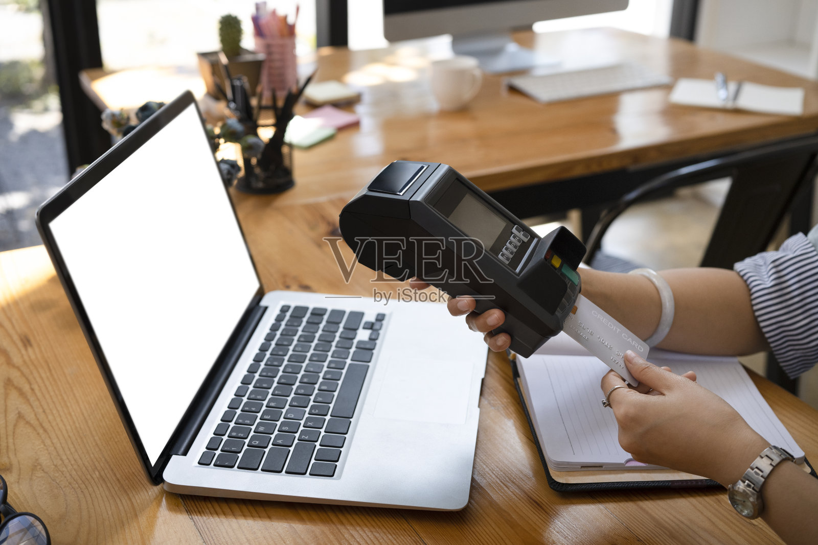 年轻女子在读卡机里刷信用卡。照片摄影图片