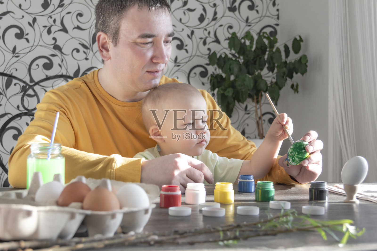 爸爸和孩子为复活节画彩蛋。照片摄影图片