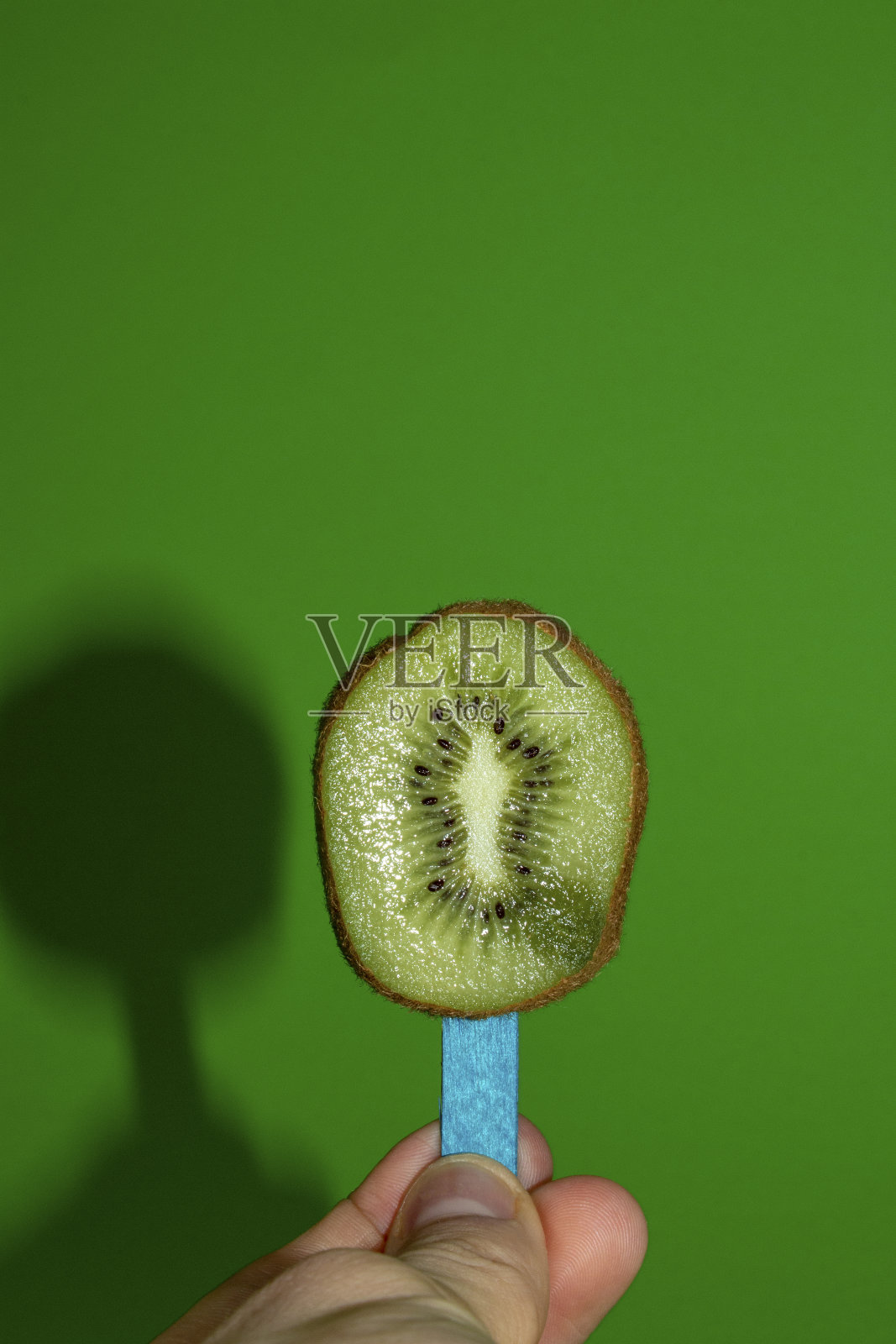 奇异果在木棒上，夏季组合水果冰淇淋在手中，创意概念在春天的绿色背景上照片摄影图片