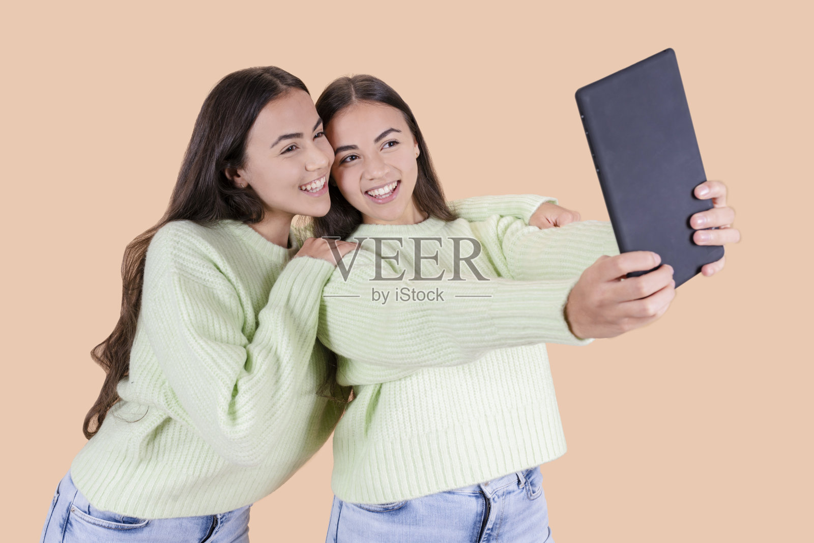 两名西班牙裔双胞胎姐妹用平板电脑自拍照片摄影图片