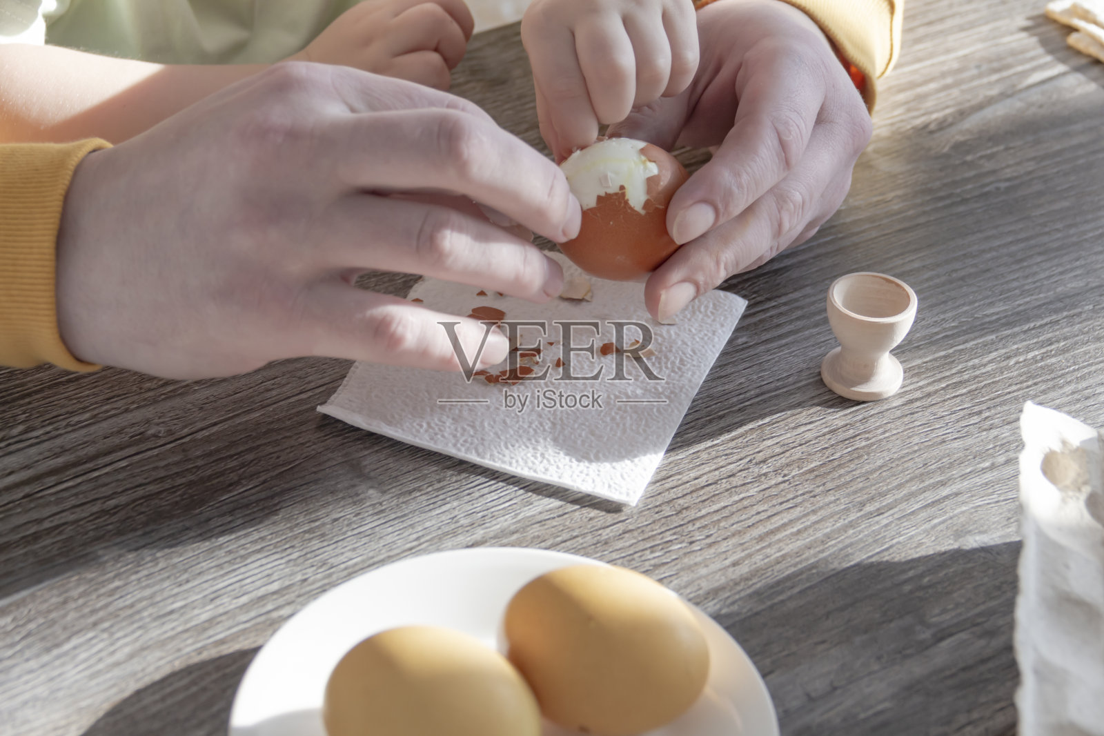 一位父亲和他的小儿子一起庆祝复活节。他们打鸡蛋，吃鸡蛋，吃早餐。爸爸教孩子。照片摄影图片