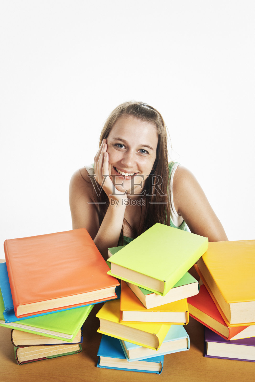 美丽的微笑的学生坐在成堆的书中，不为她有多少要学习照片摄影图片